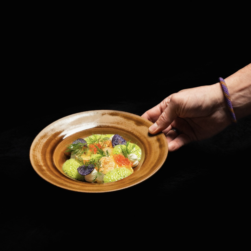 Seafood dish with salmon roe, dill and garnishes on a brown plate
