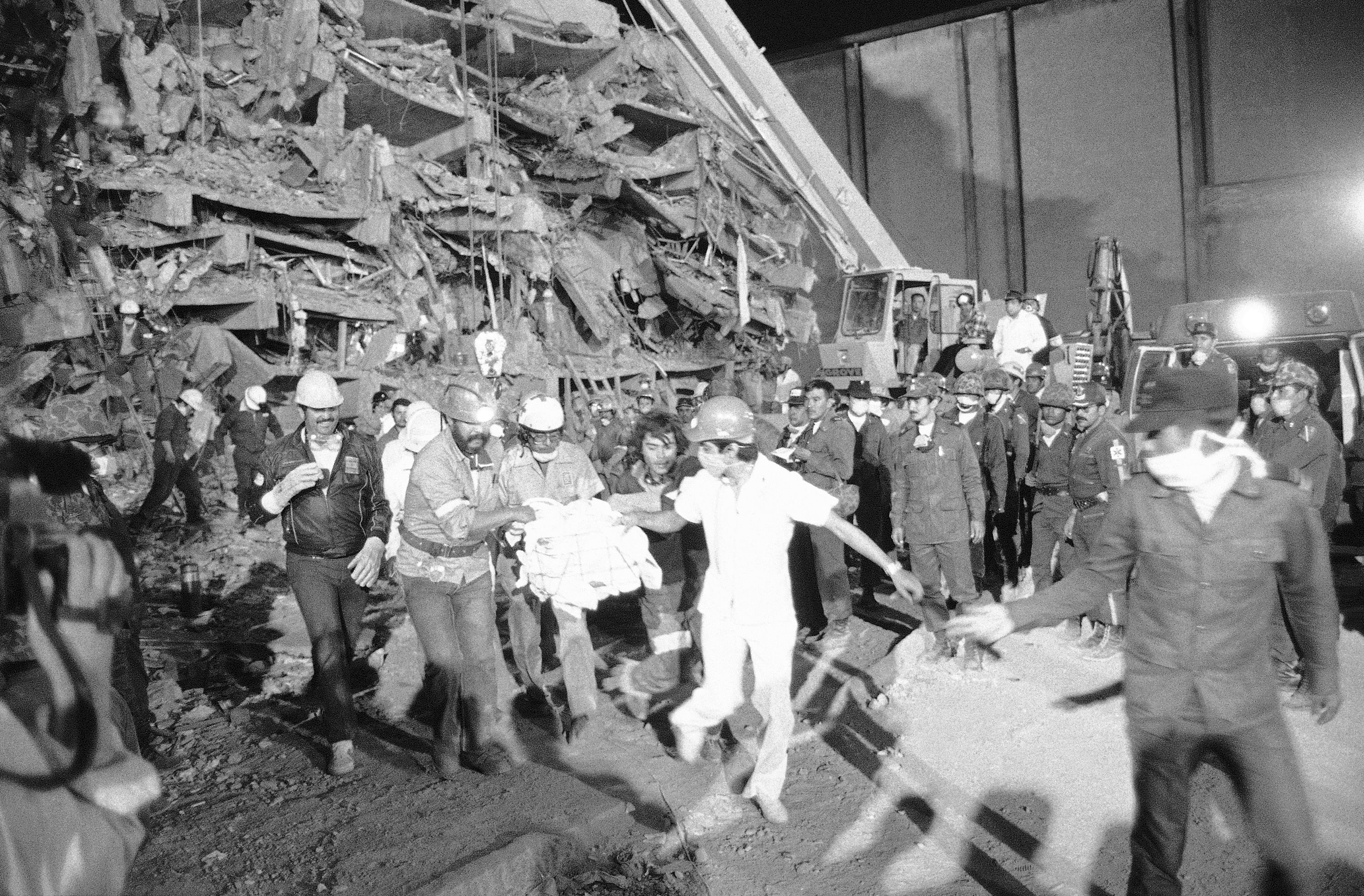 FILE - Emergency workers carry hospital patient Rubalcada Pena after rescuing him from the rubble of Mexico City's Juarez Hospital, which was destroyed by an earthquake, Sept. 26, 1985. (Jack Smith - AP)