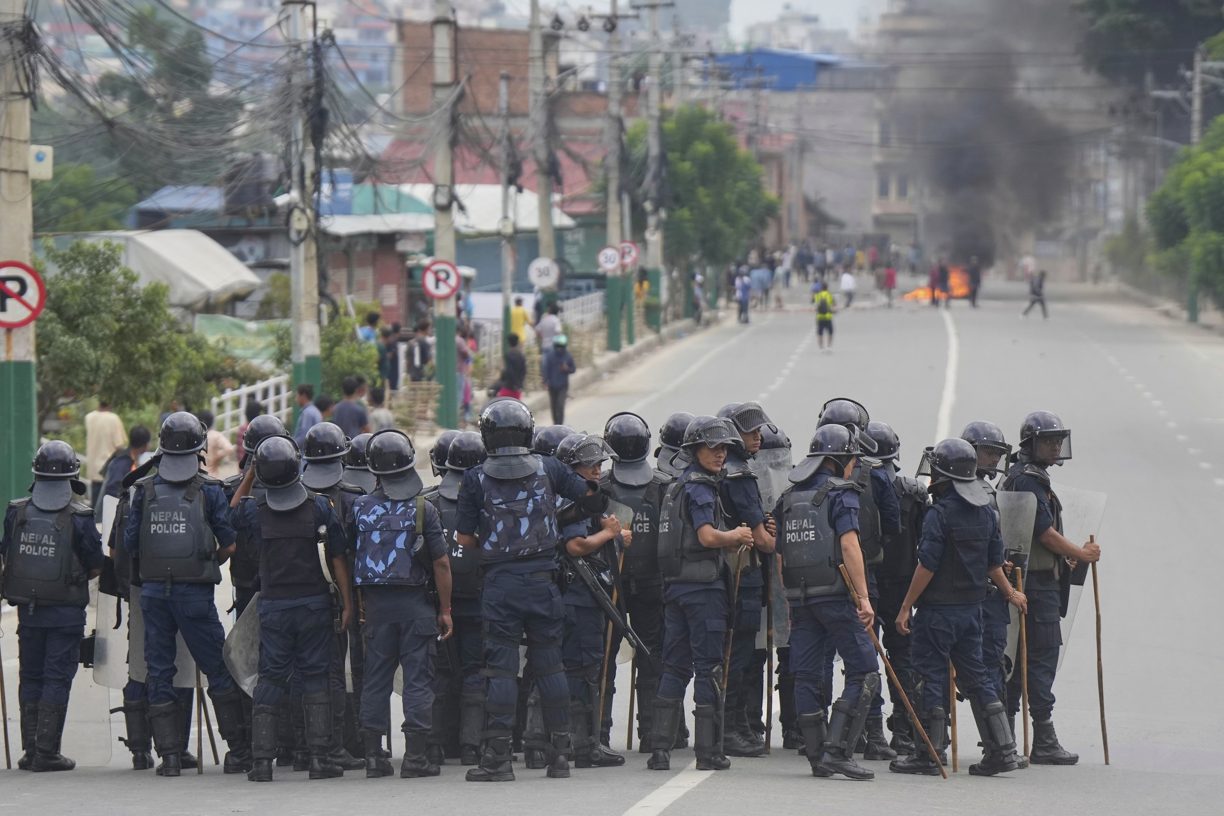 Policemen in riot gear stand guard on a street as protesters burn tires violating curfew orders in Kathmandu, Nepal, Tuesday, Sept. 9, 2025 after Nepal’s government lifted its ban on social media platforms after violent street protests. (Niranjan Shrestha - AP)