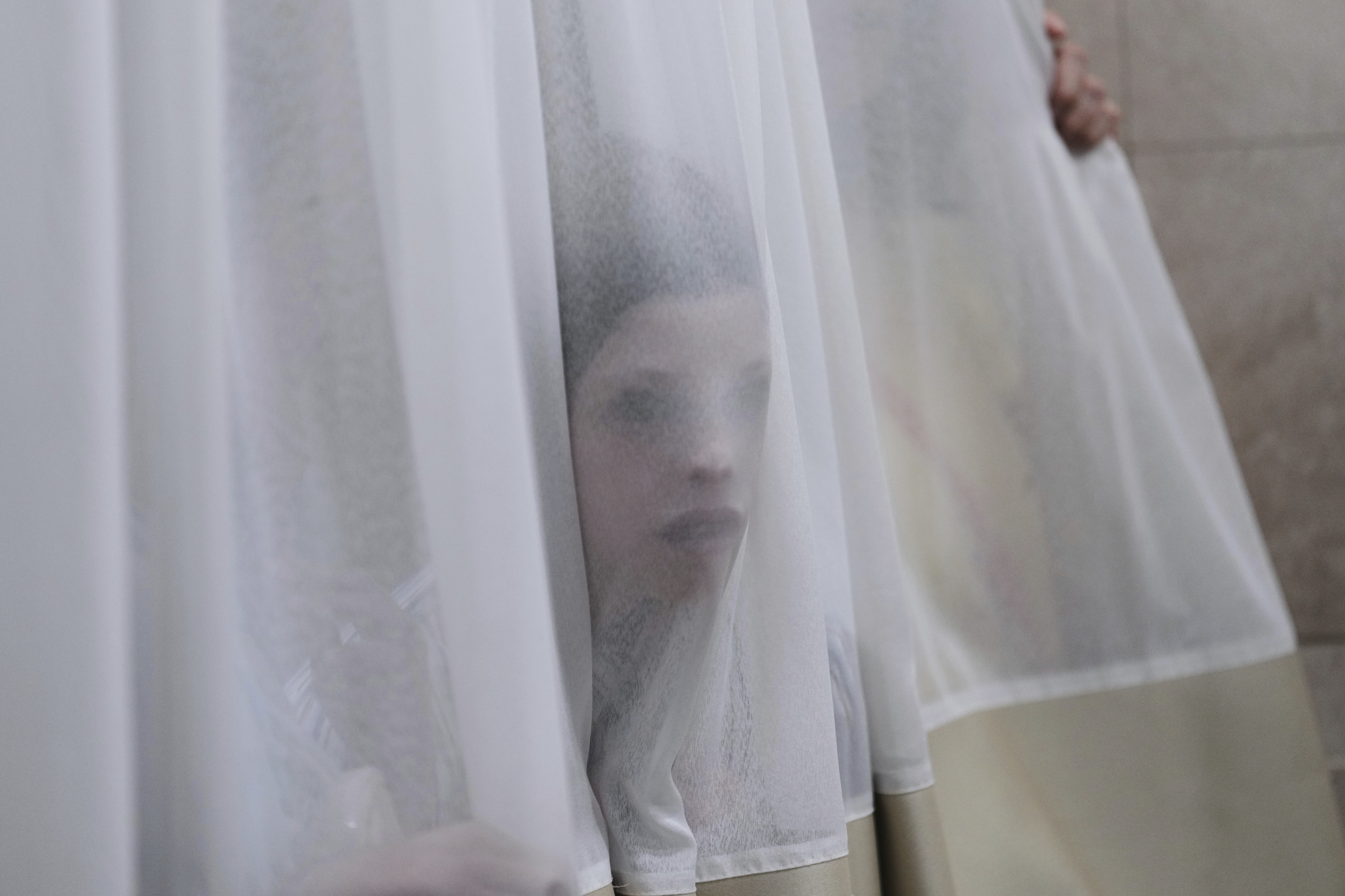 A mourner looks trough a curtain during the funeral of Levi Yitzhak Pash, who was killed along with five other Israelis in a shooting attack by two Palestinian gunmen at a bus stop in Jerusalem Monday, Sept. 8, 2025. (Ariel Schalit - AP)