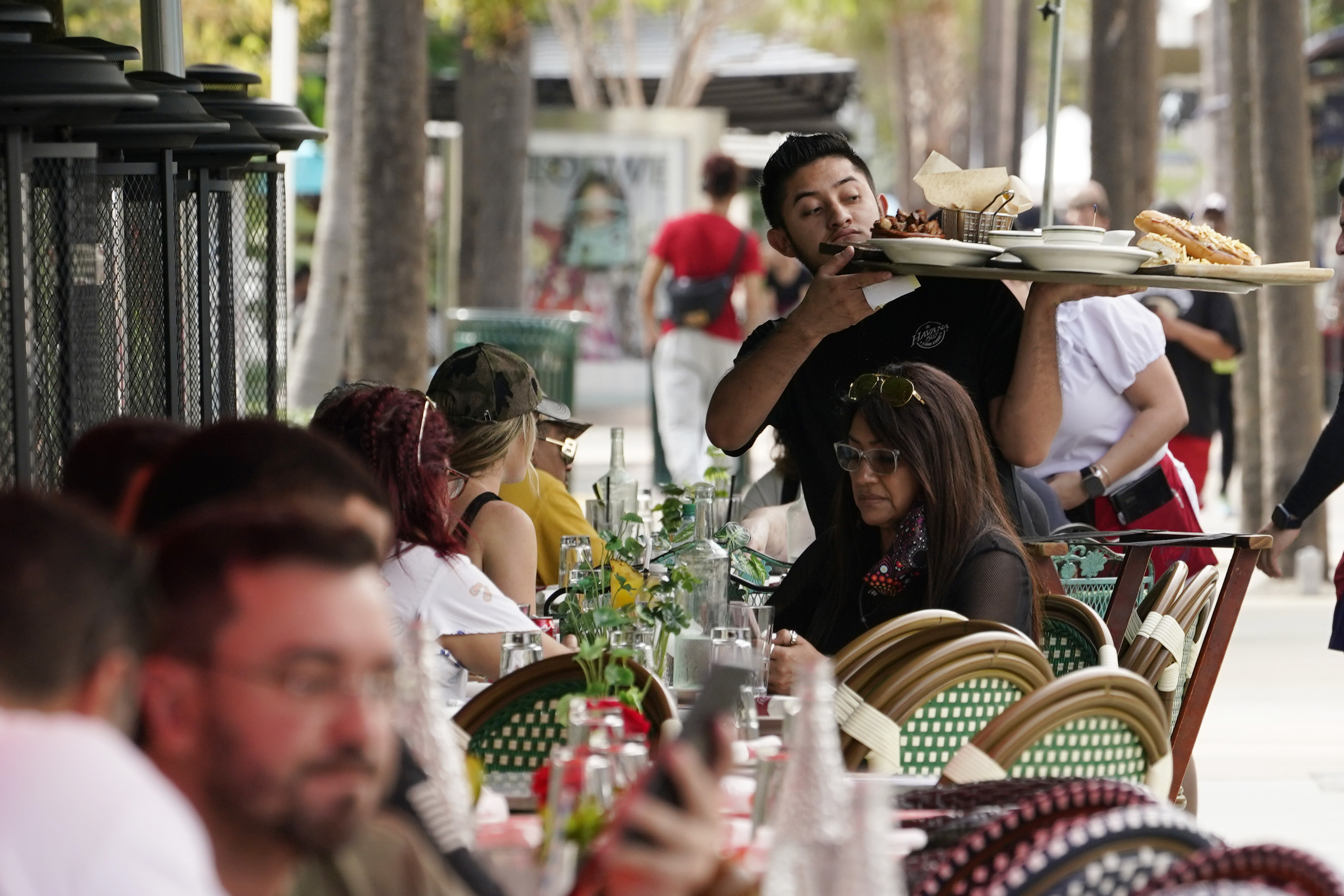 FILE - A waiter delivers food to patrons at a restaurant, Jan. 21, 2022, in Miami Beach, Fla. (Marta Lavandier - AP)