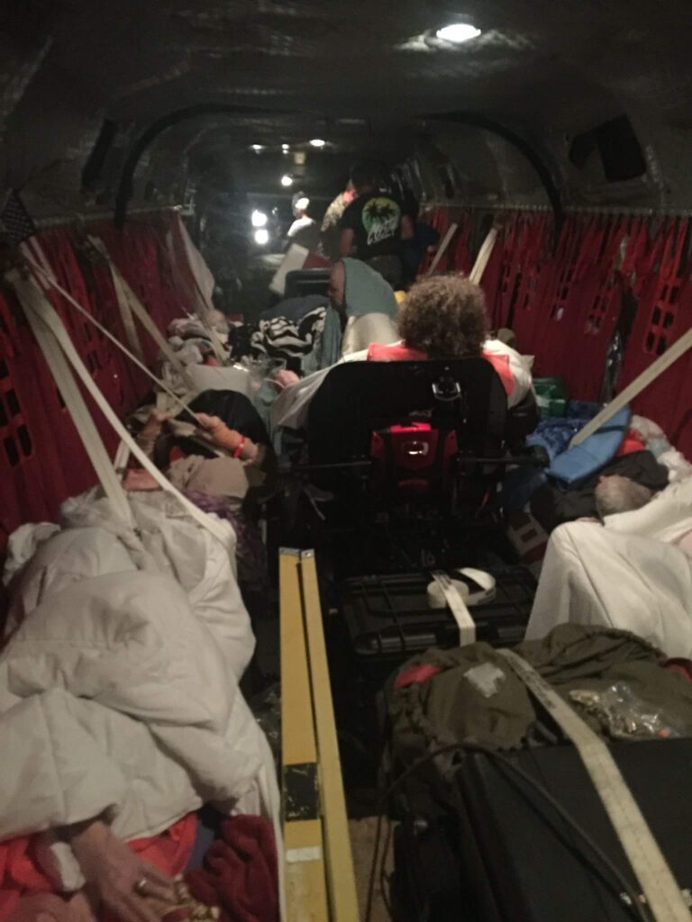 Seniors rescued from a flood are depicted inside a dark helicopter. 