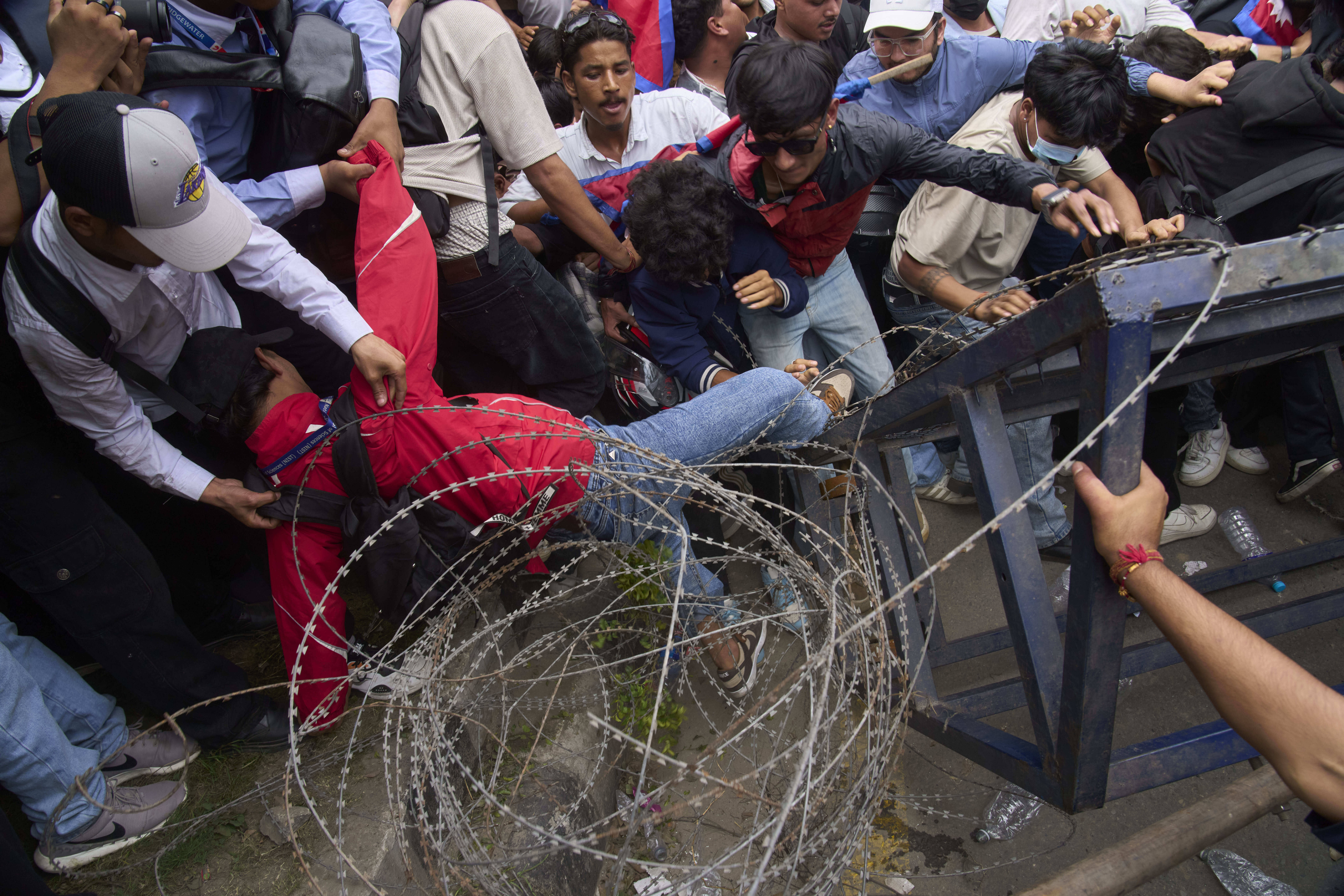 A protester falls down during clashes with riot police outside the parliament building in Kathmandu, Nepal, Monday, Sept. 8, 2025. (Niranjan Shrestha - AP)