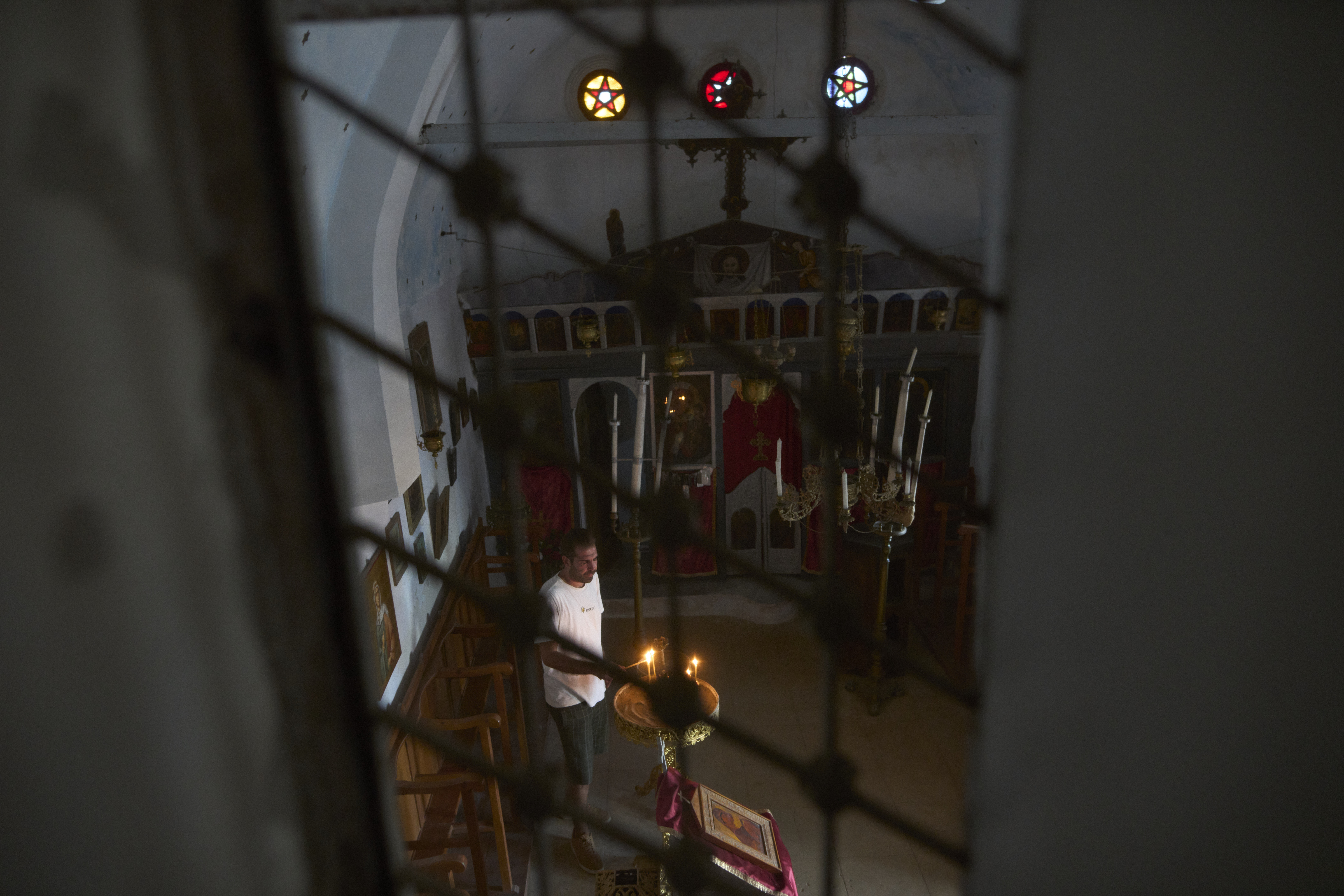 Konstantinos Vasilopoulos lights a candle at the Panagia Faneromeni family-owned chapel near the village of Triantaros, on the island of Tinos, Greece, Saturday, Sept. 6, 2025. (Petros Giannakouris - AP)