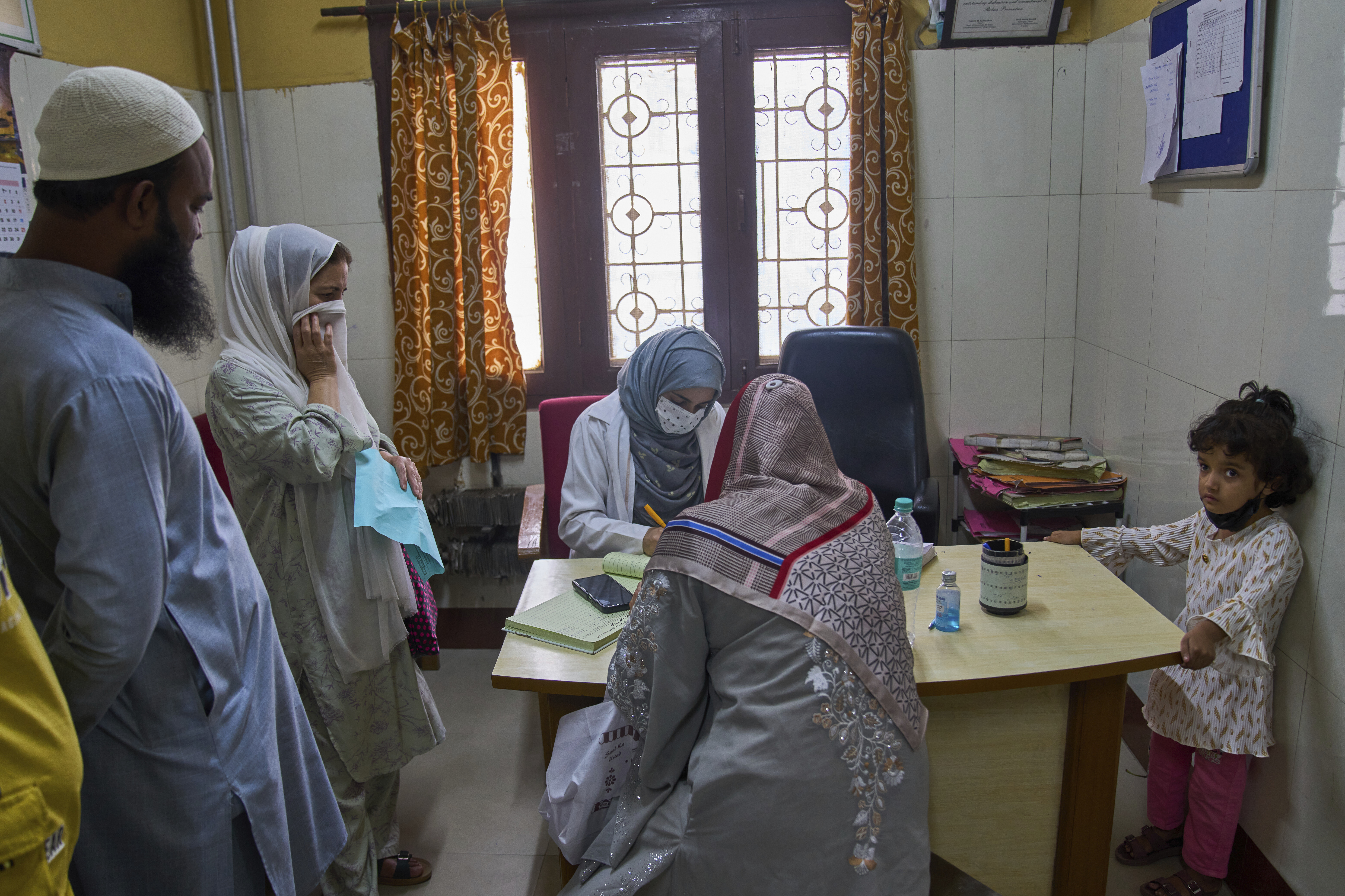 Rehmat Ashraf, 6, right, who was attacked by a dog outside her house, looks on as Insha Rehman, center in grey scarf, records patient details inside the anti-rabies clinic at a hospital in Srinagar, Indian controlled Kashmir, Thursday, Sept. 18, 2025. (Dar Yasin - AP)