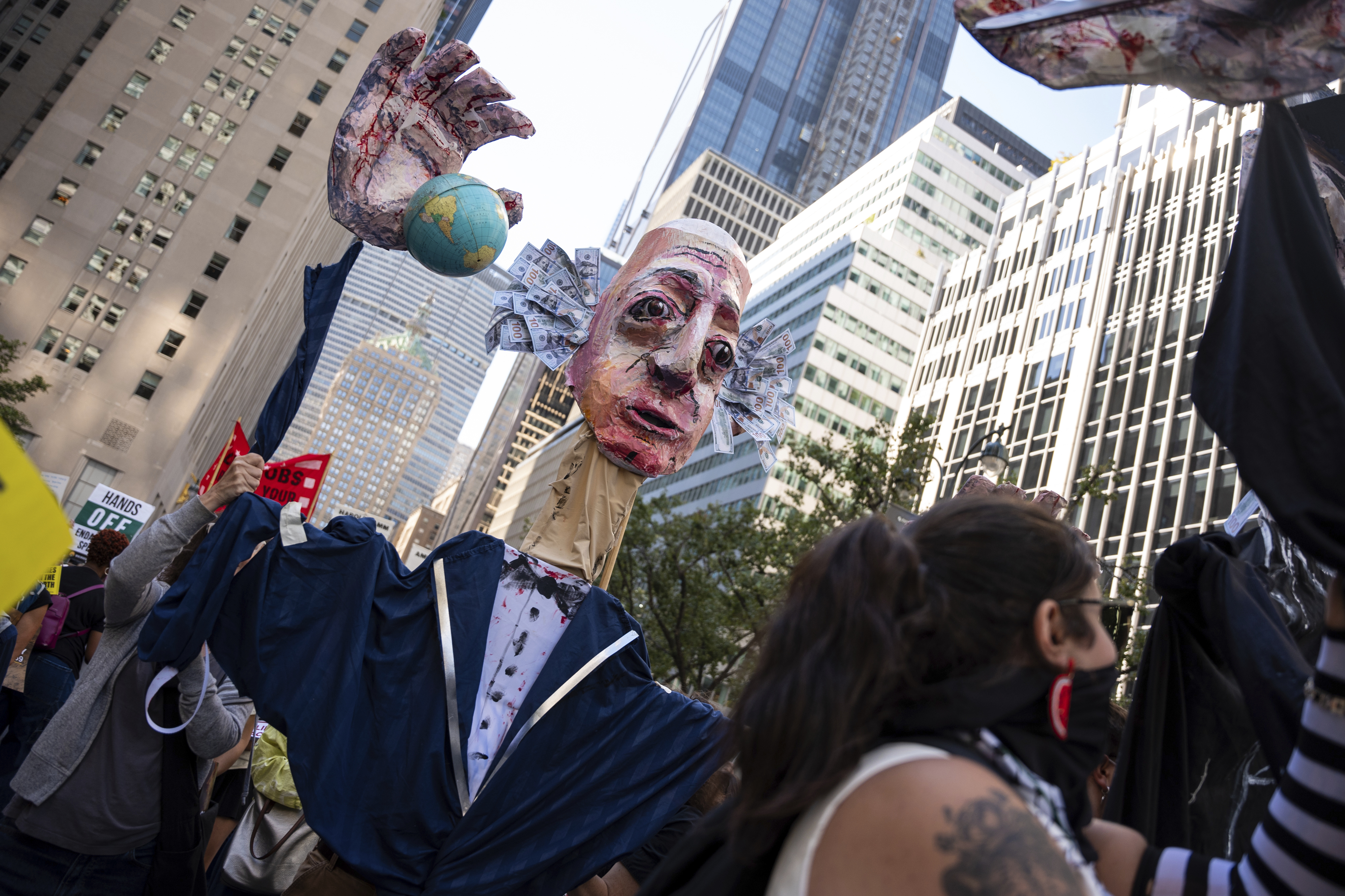 An art piece of Jeff Bezos with bloody hands carrying the globe is marched through Manhattan at the 