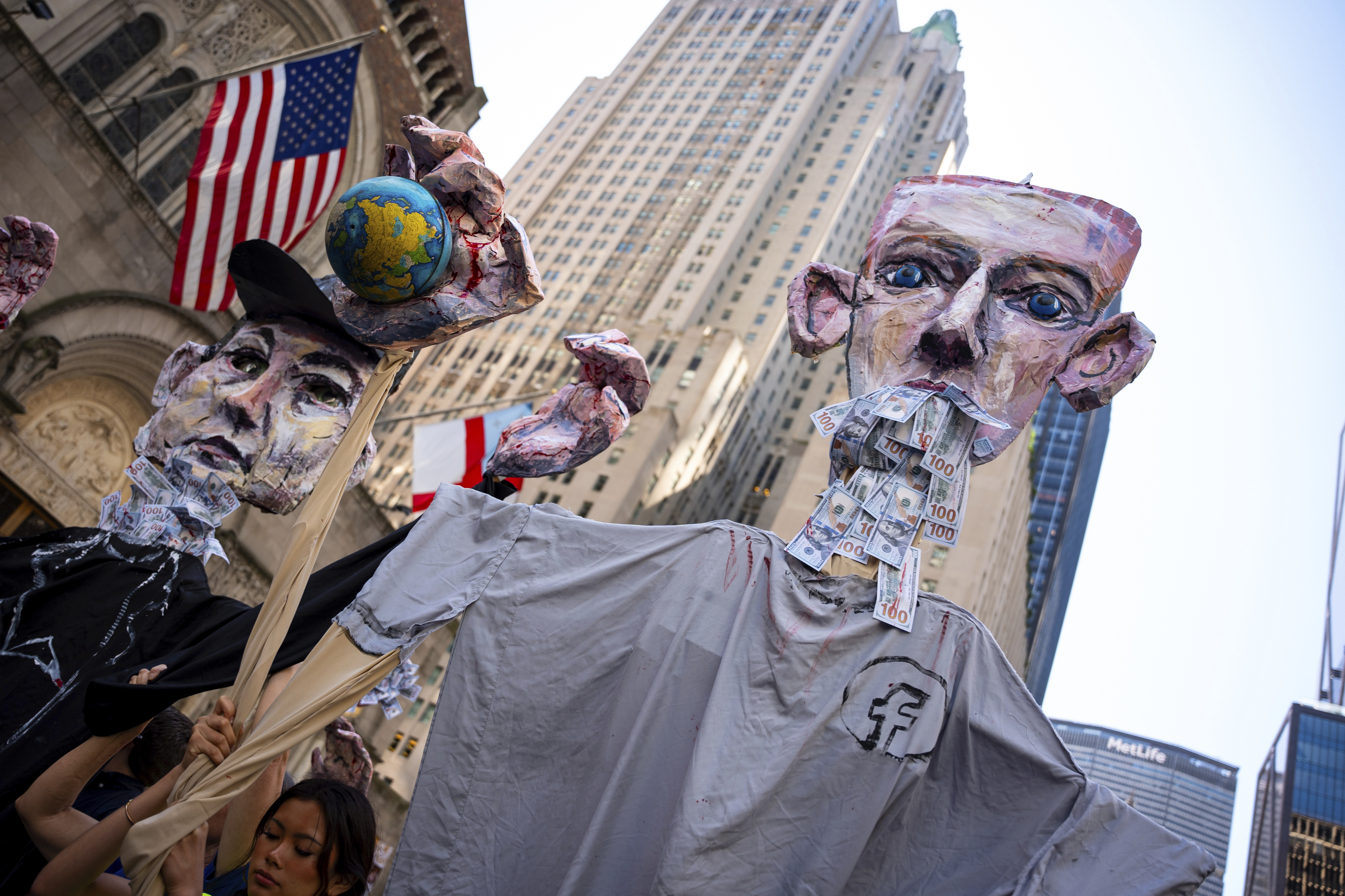 Art pieces of Mark Zuckerberg and Elon Musk with bloody hands carrying globes are marched through Manhattan at the 