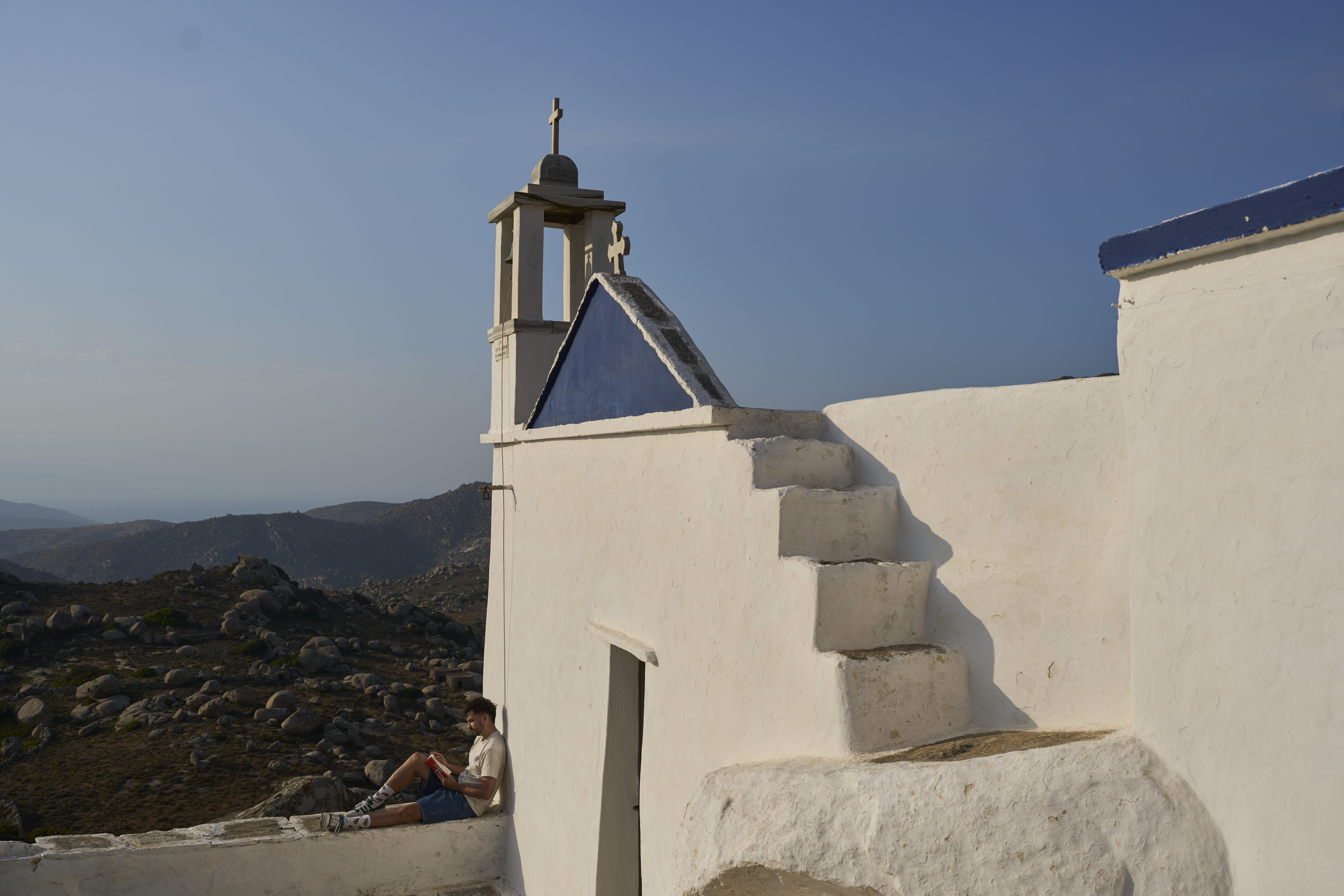 Giannis Kafantaris 26, reads a book outside Panagia Theoskespasti, the chapel his family co-owns near the village of Falatados, on the Aegean island of Tinos, Greece, Friday, Sept. 5, 2025. (Petros Giannakouris - AP)