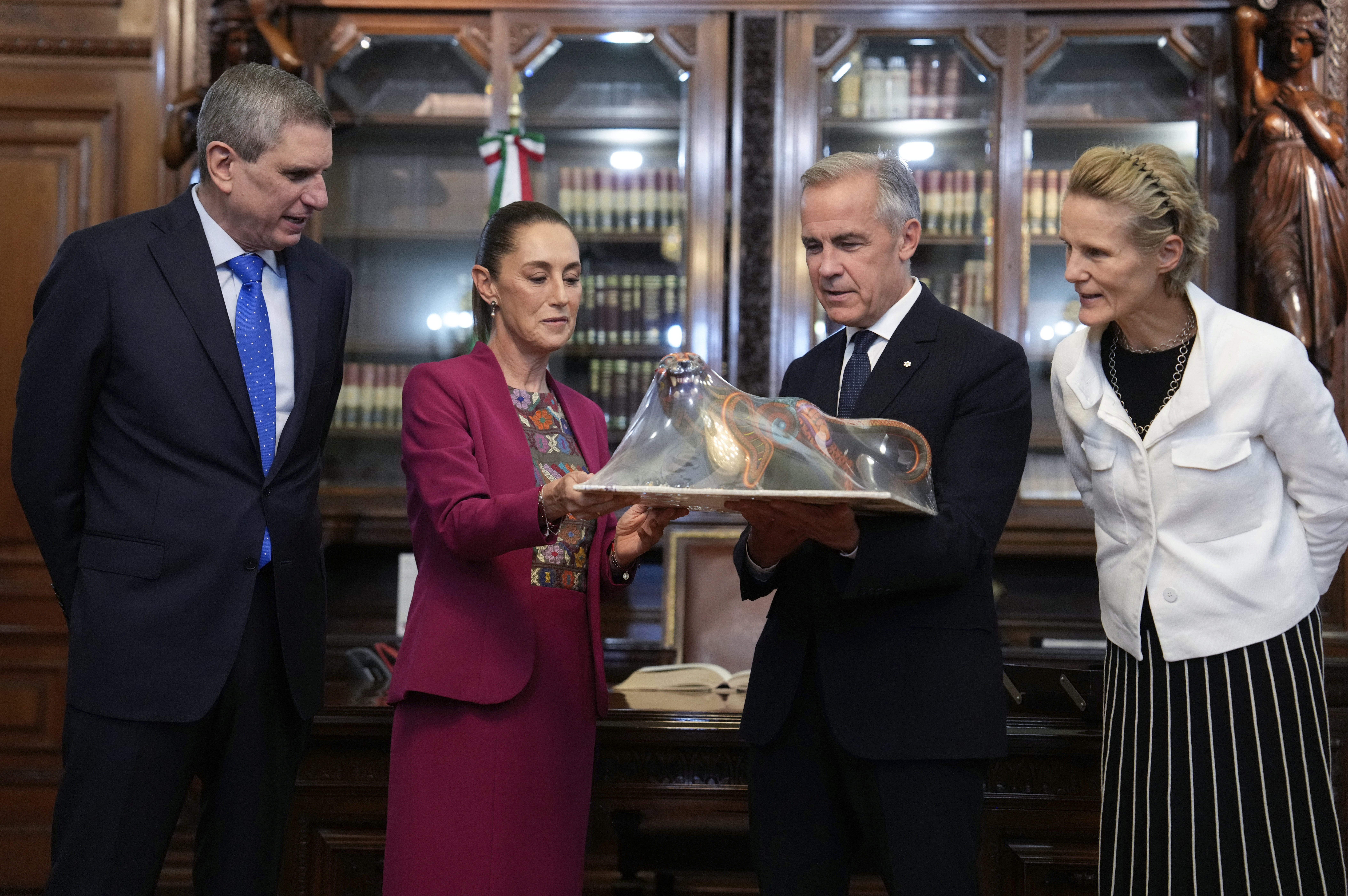 Jesus Maria Tarriba, left, and Diana Fox Carney, right, look on as Mexican President Claudia Sheinbaum presents a gift to Canada's Prime Minister Mark Carney at the National Palace in Mexico City, Thursday, Sept. 18, 2025. (Adrian Wyld - The Canadian Press)