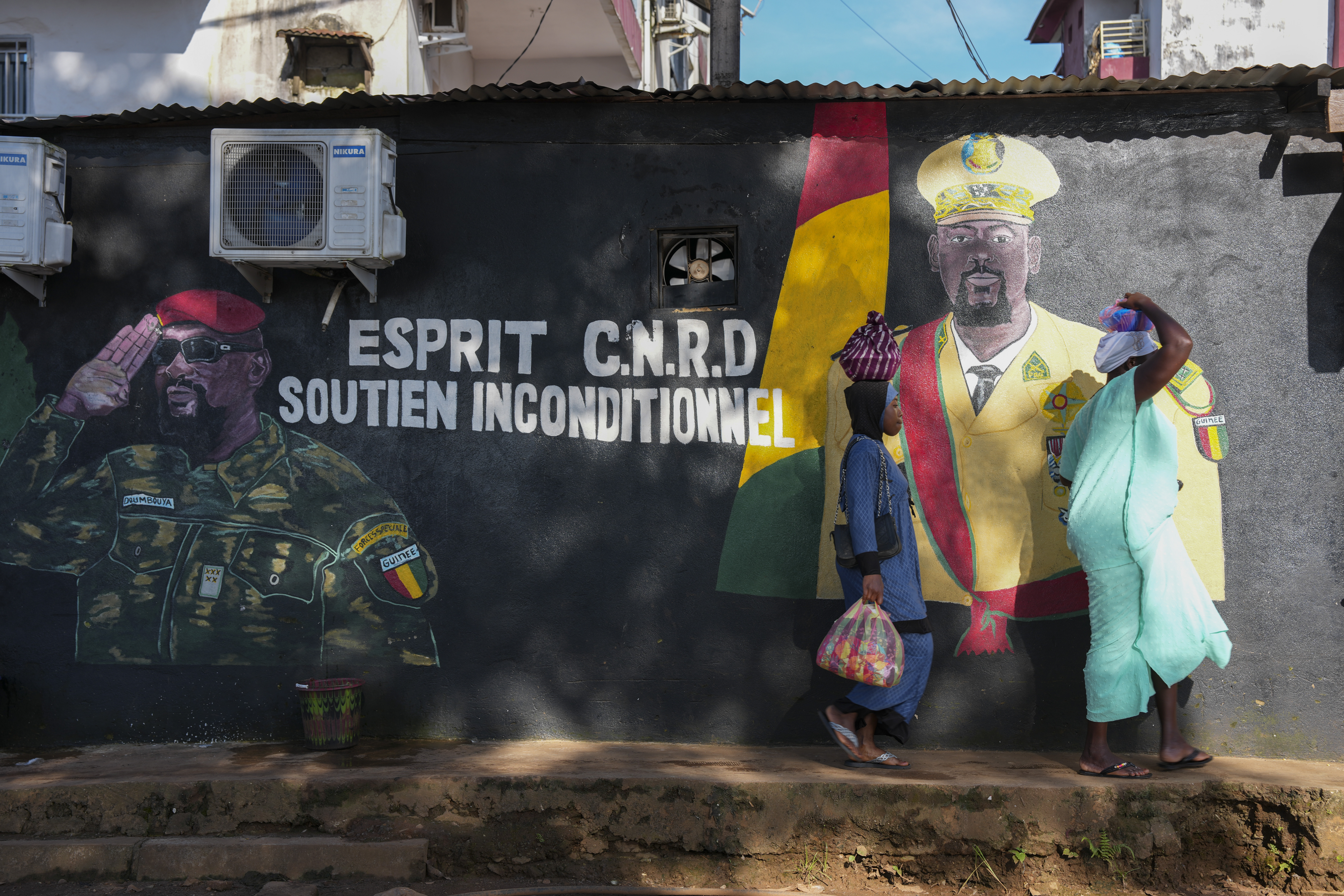 CORRECTS TITLE OF MILITARY LEADER People walk past a mural showing Guinea's interim president, Gen. Mamadi Doumbouya, ahead of the constitutional referendum in Conakry, Guinea, Wednesday, Sept. 17, 2025. (Misper Apawu - AP)