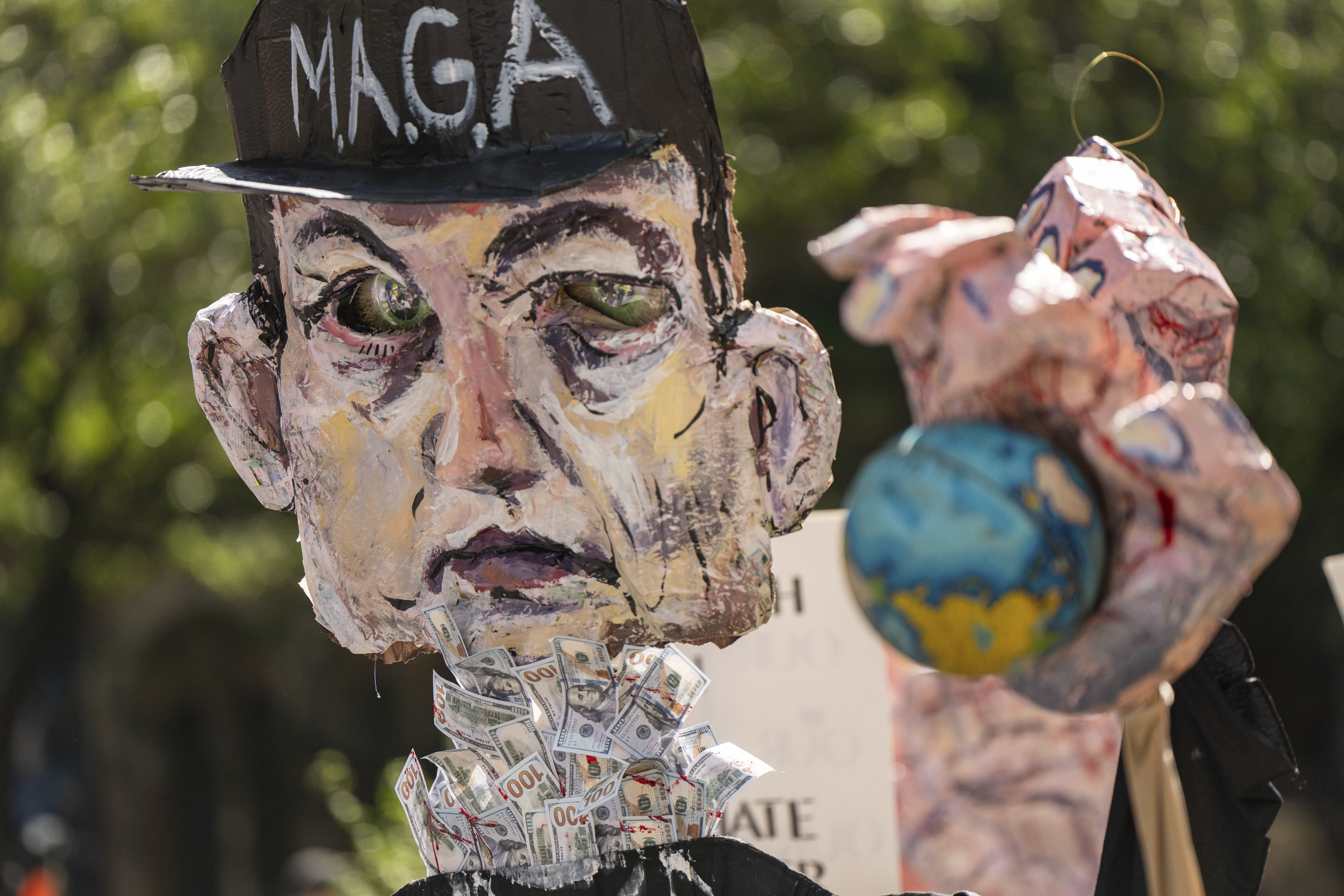 An effigy representing Elon Musk with a bloody hand holding a globe is marched through Manhattan at the 