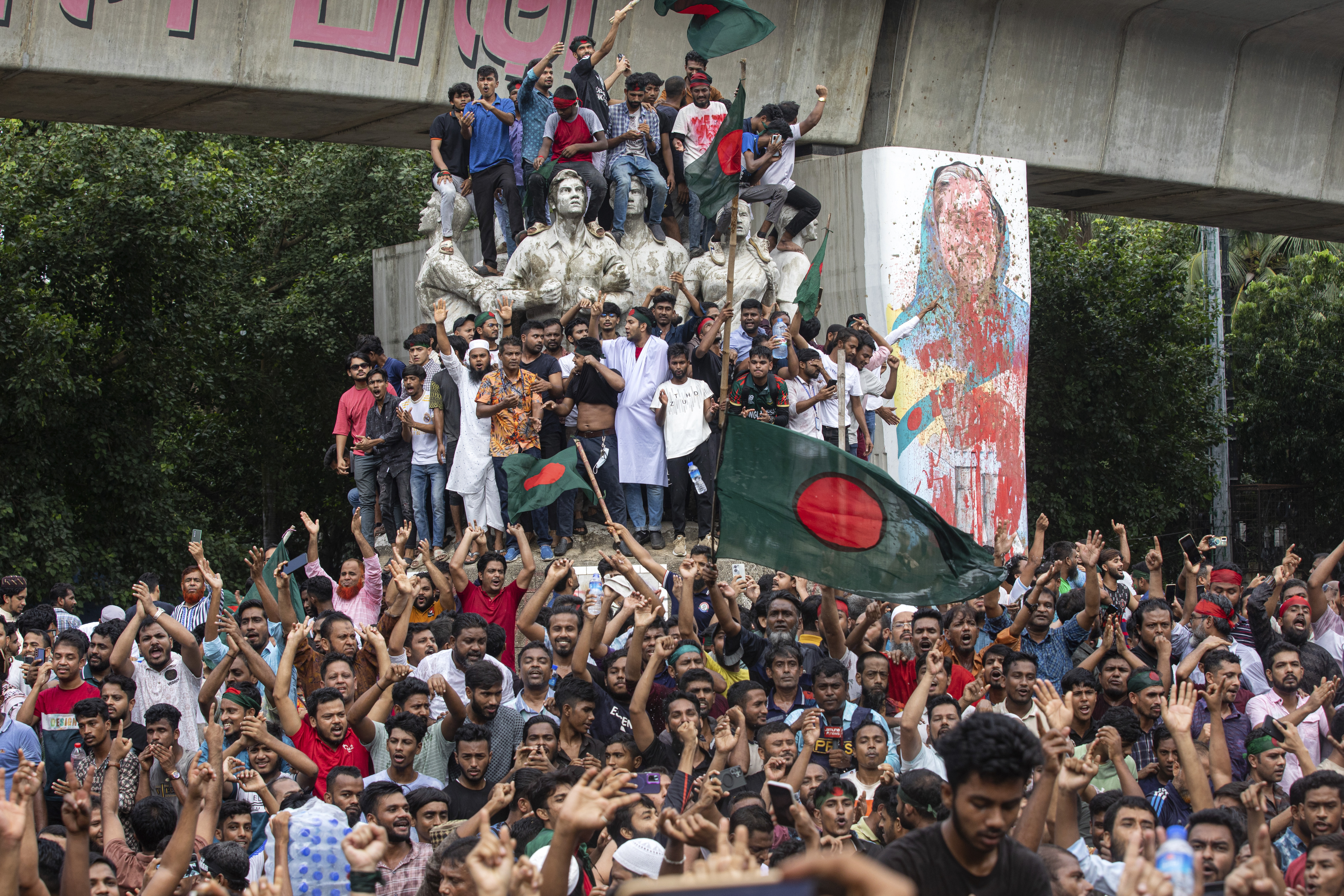 FILE -Protesters climb a public monument as they celebrate the news of Prime Minister Sheikh Hasina's resignation, in Dhaka, Bangladesh, Aug. 5, 2024. (Rajib Dhar - AP)