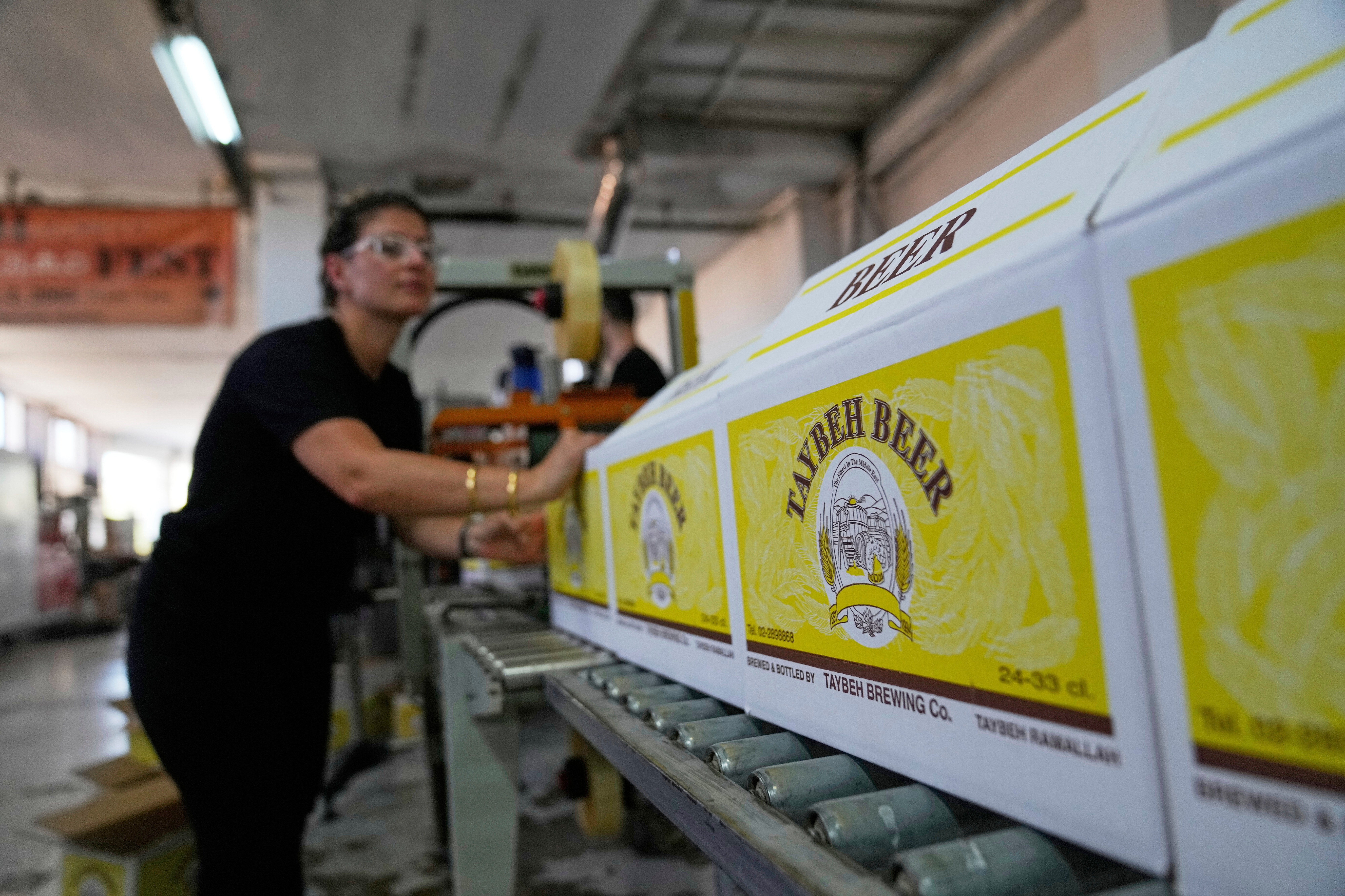 Nadin Khoury, 36, packs Taybeh beer products on a production line of the Family's Palestinian Taybeh Brewery Co. in the West Bank town of Taybeh, Saturday, Sept. 6, 2025. (Nasser Nasser - AP)