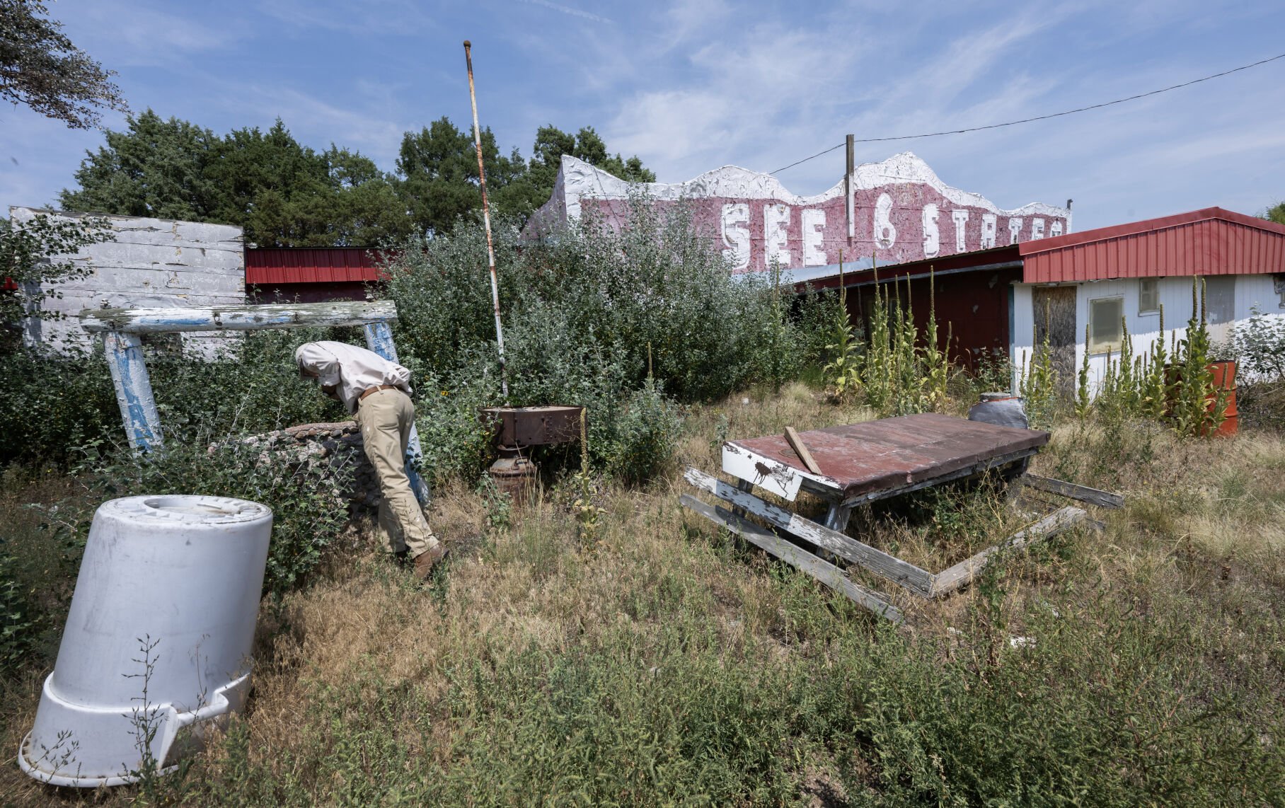 Reed Weimer looks down an old well outside the World's Wonder View Tower Thursday, Aug. 14, 2025, outside Genoa, Colo., to see skelton of an snake that must of fallen into the well years ago. (The Gazette, Christian Murdock) (Christian Murdock, The Gazette)