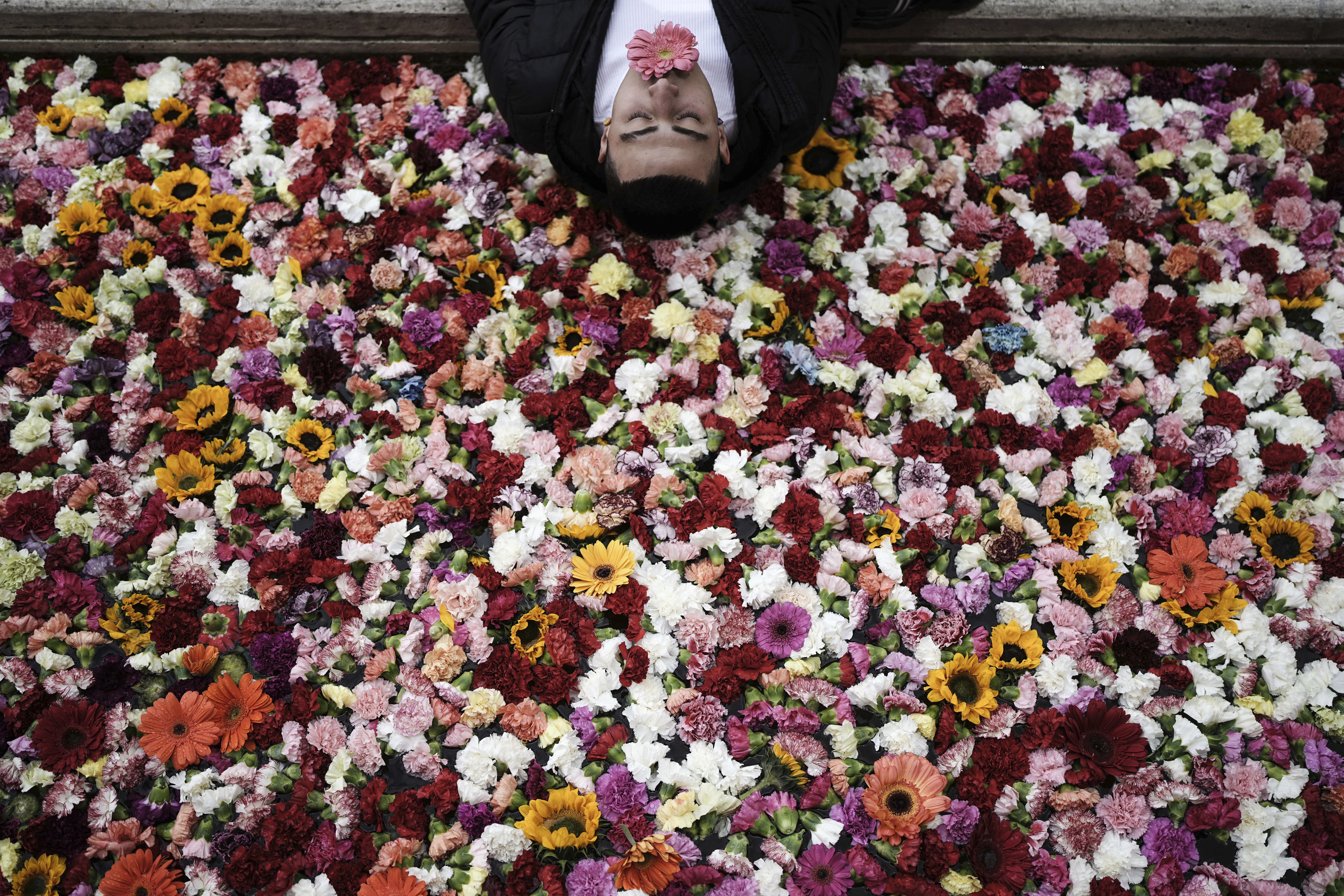 A pedestrian poses for a photo on the edge of an installation, a canal filled with flowers, during the opening of the city’s first art biennial in downtown Bogota, Colombia, Saturday, Sept. 20, 2025. (Ivan Valencia - AP)