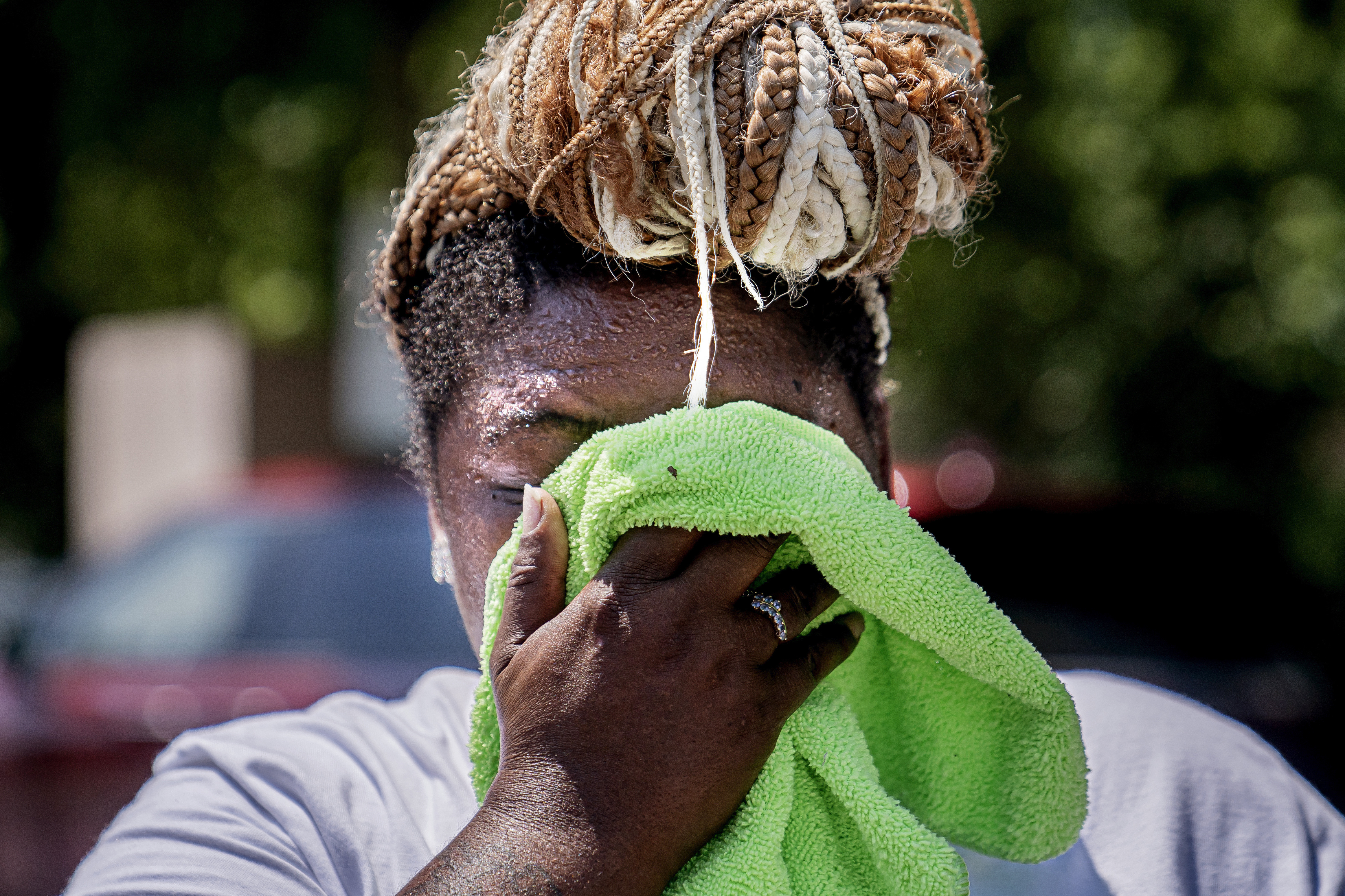 FILE - Nicole Brown wipes sweat from her face while setting up her beverage stand near the National Mall on July 22, 2022, in Washington. (Nathan Howard - FR171771 AP)