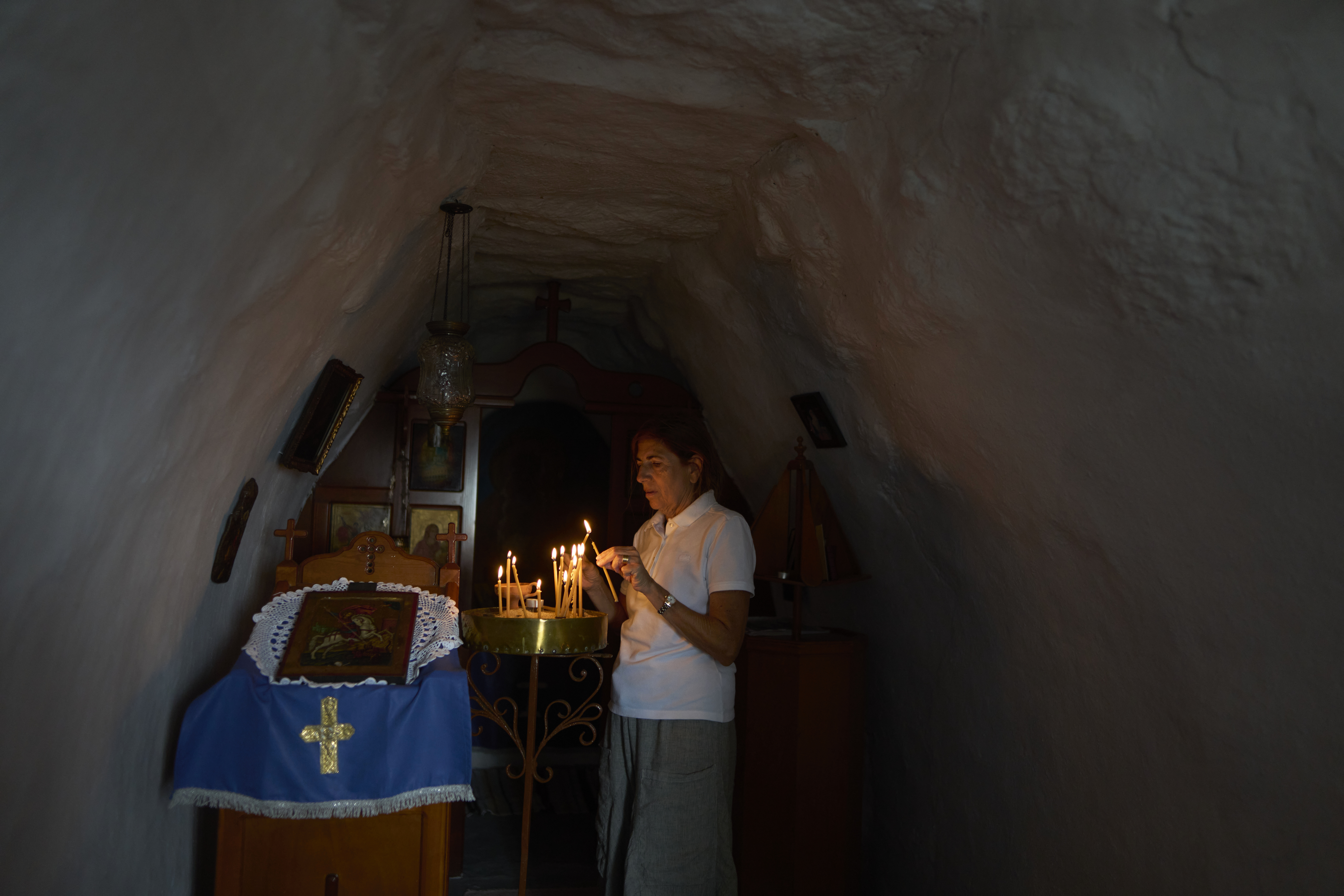 Dragana Grozdanovic, whose son was married in a family chapel in Tinos, lights a candle in Agios Giorgos (St. George), a 200-year-old chapel near the village of Volax on Tinos island, Greece, Thursday, Sept. 4, 2025. (Petros Giannakouris - AP)
