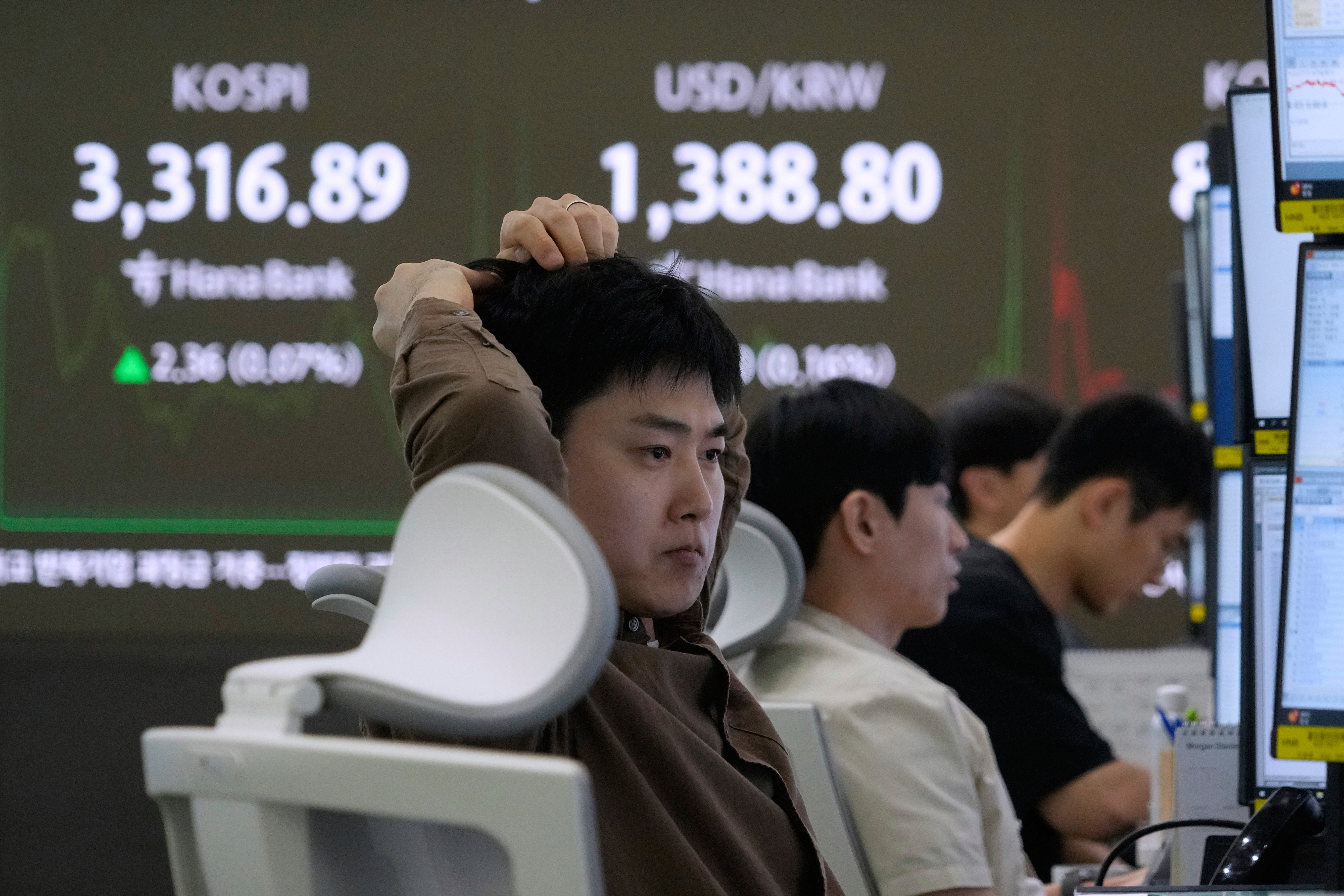 A currency trader watches monitors near a screen showing the Korea Composite Stock Price Index (KOSPI), top left, and the foreign exchange rate between U.S. dollar and South Korean won at the foreign exchange dealing room of the Hana Bank headquarters in Seoul, South Korea, Thursday, Sept. 11, 2025. (Ahn Young-joon - AP)