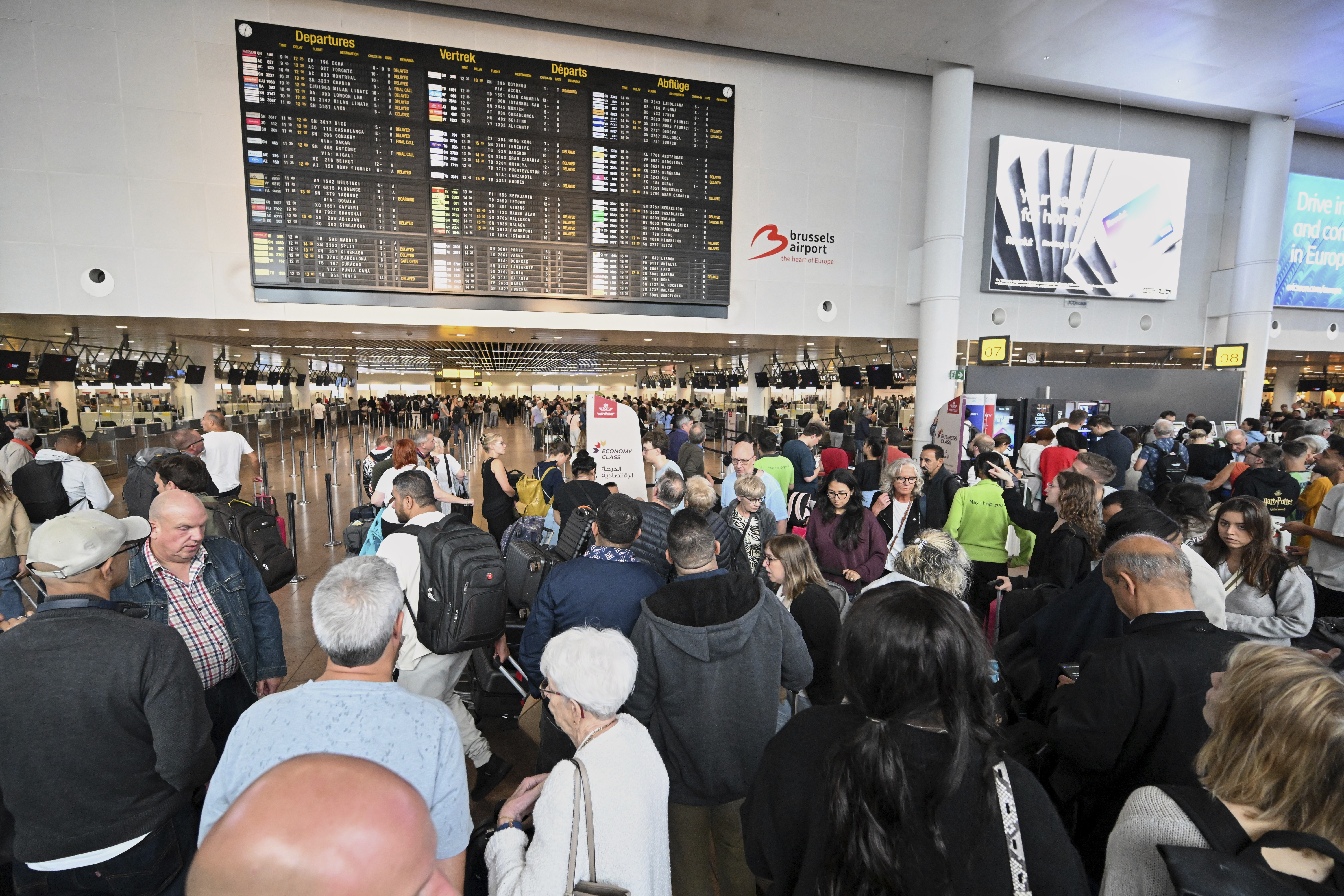 People stand in front of a departure board after a cyber attack caused delays at Brussels International Airport in Zaventem, Belgium, Saturday, Sept. 20, 2025. (Harry Nakos - AP)