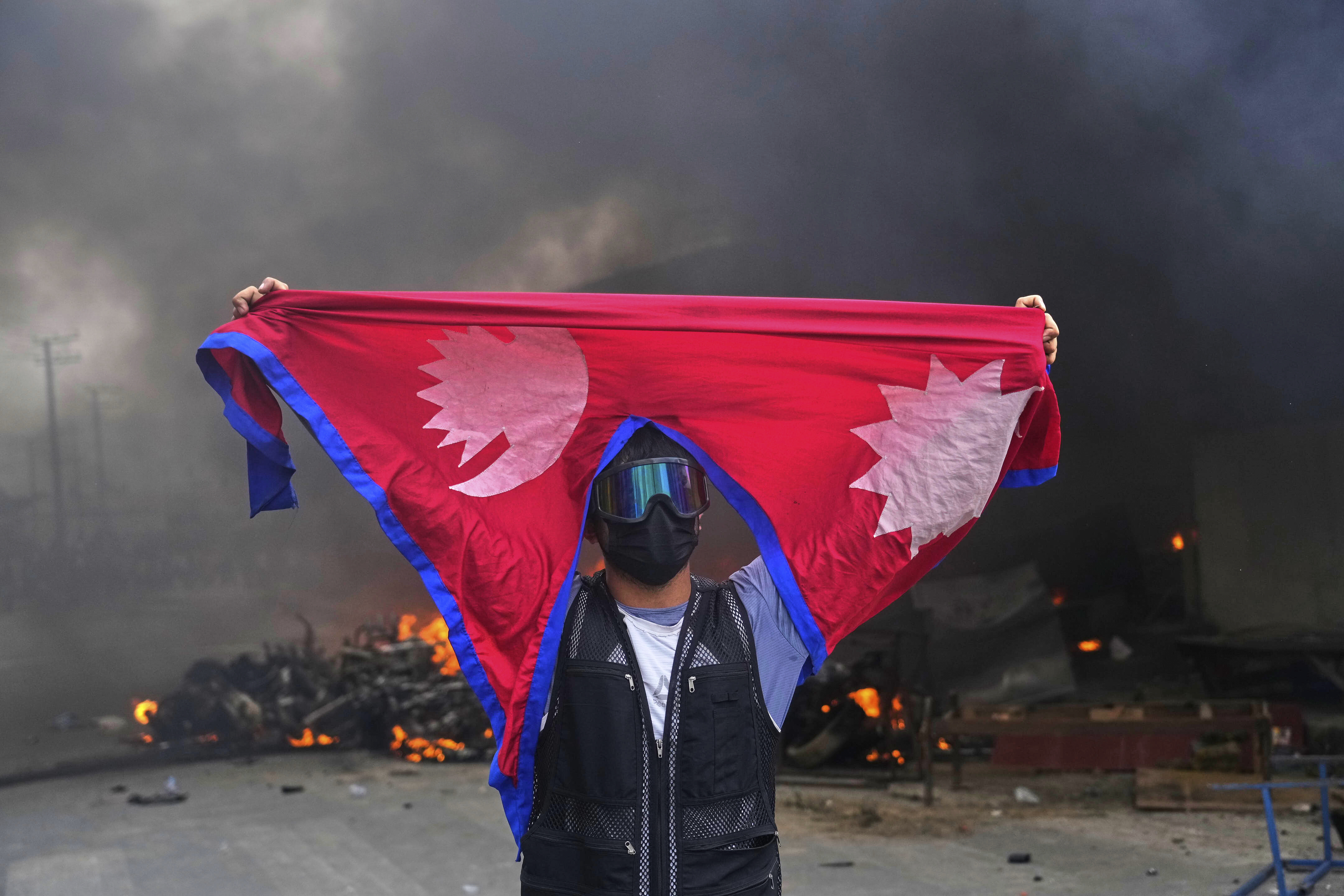 A protester shouts slogans carrying national flag after burning down a police station during protests against social media ban and corruption in Kathmandu, Nepal, Tuesday, Sept. 9, 2025. (Niranjan Shrestha - AP)