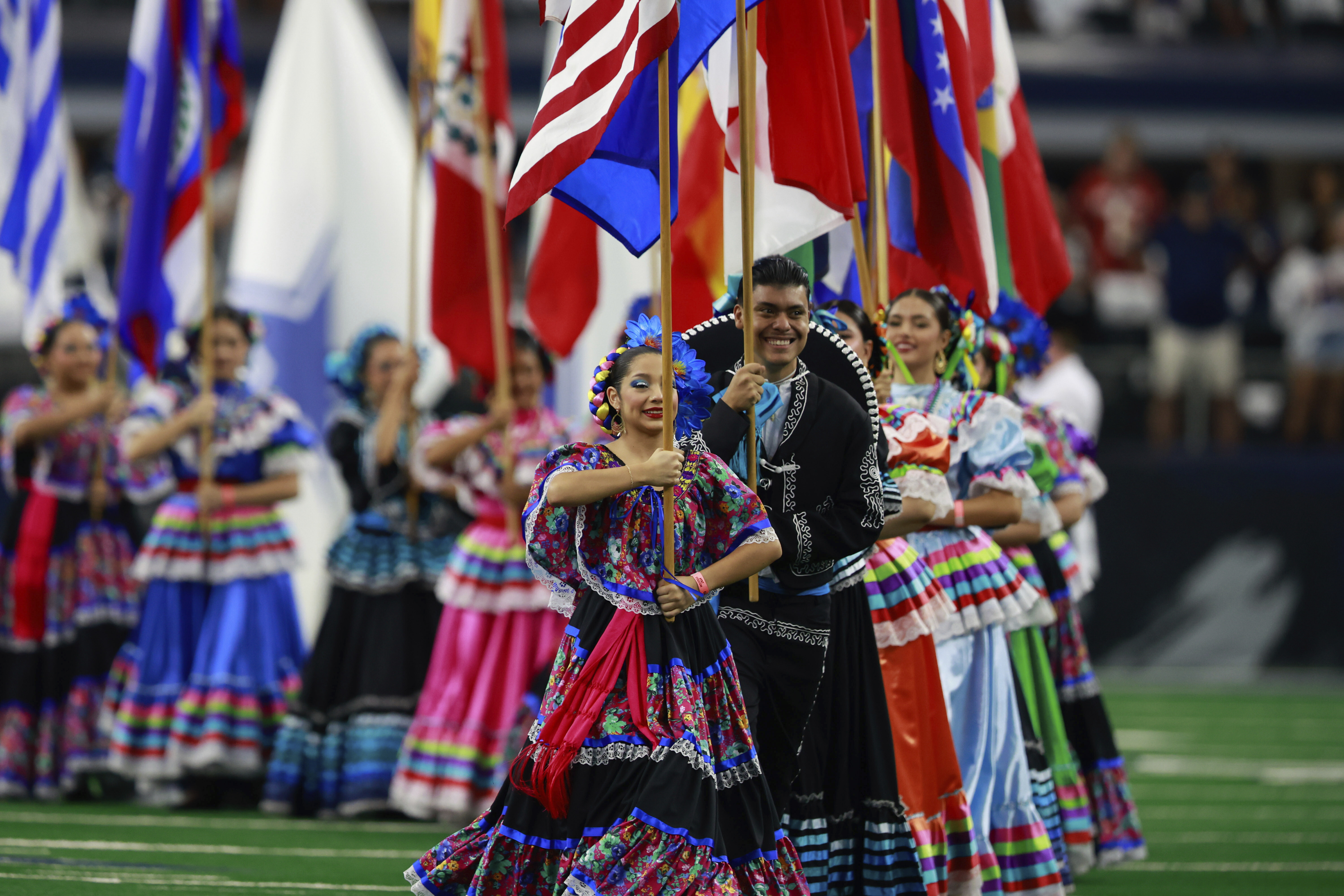 FILE - National flags from Latin American countries are displayed on the field during a celebration of Hispanic Heritage Month before an NFL football game between the Baltimore Ravens and Dallas Cowboys in Arlington, Texas, Sunday, Sept. 22, 2024. (Gareth Patterson - FR170364 AP)