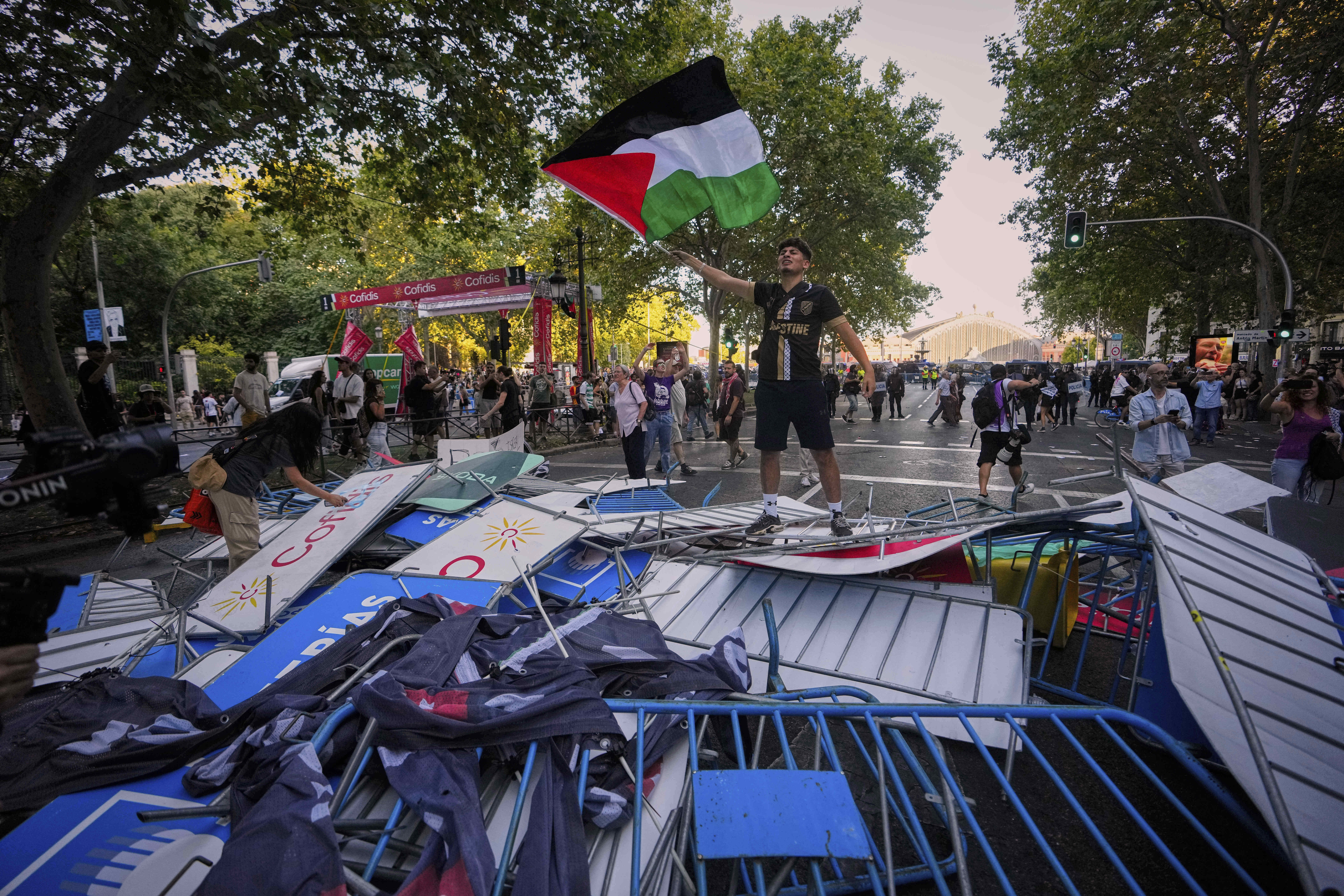 A protester waves a Palestinian flag on top of fences used as barricades to block the street to disrupt the twenty-first stage of the Spanish cycling race La Vuelta, from Alalpardo to Madrid, Spain, Sunday, Sept. 14, 2025. (Manu Fernandez - AP)