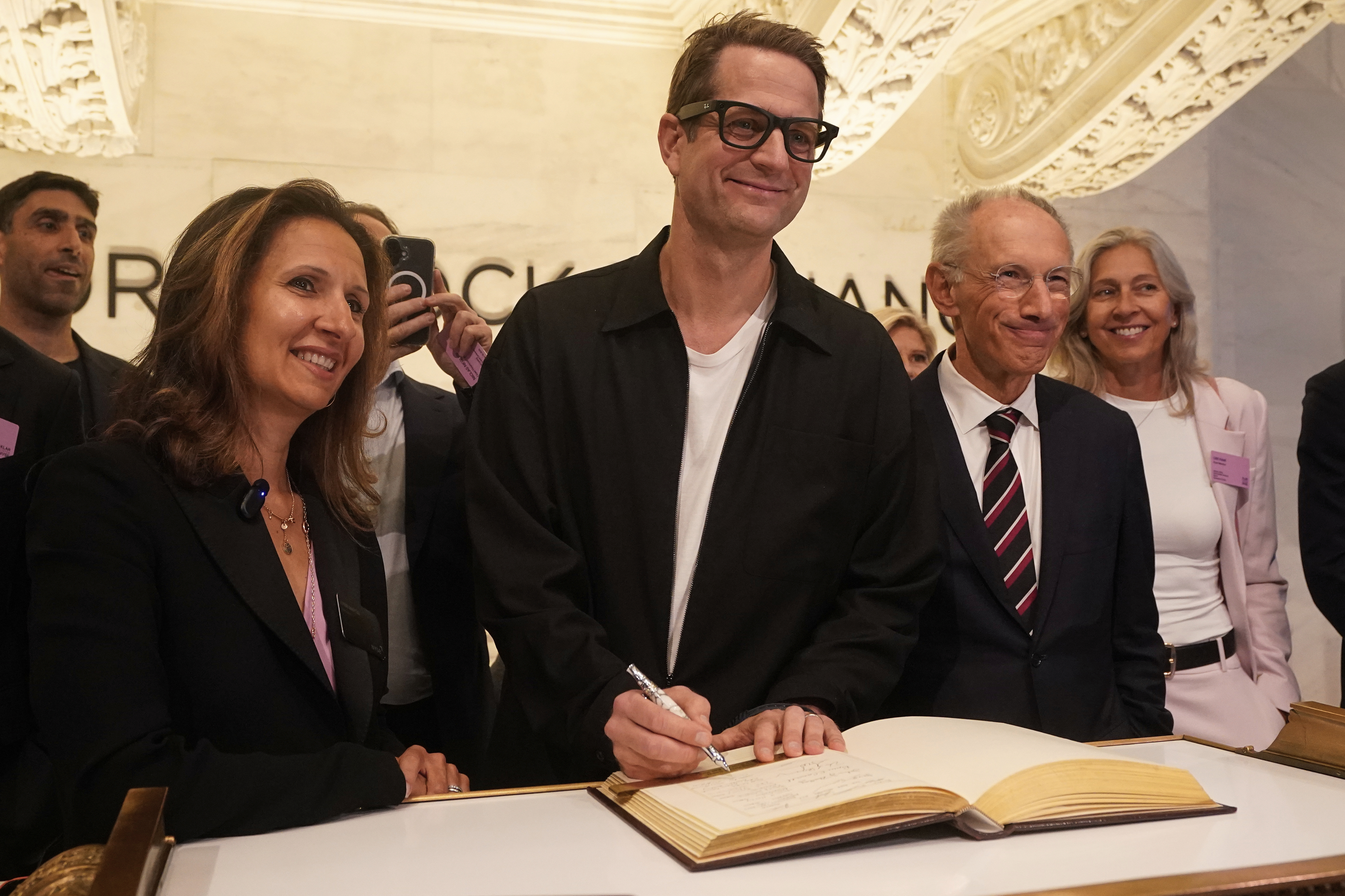 Klarna CEO Sebastian Siemiatkowski, center, accompanied by NYSE President Lynn Martin, left, and Klarna Chairman Michael Moritz, right, signs the guest book before ringing the New York Stock Exchange opening bell, Wednesday, Sept. 10, 2025. (Richard Drew - AP)