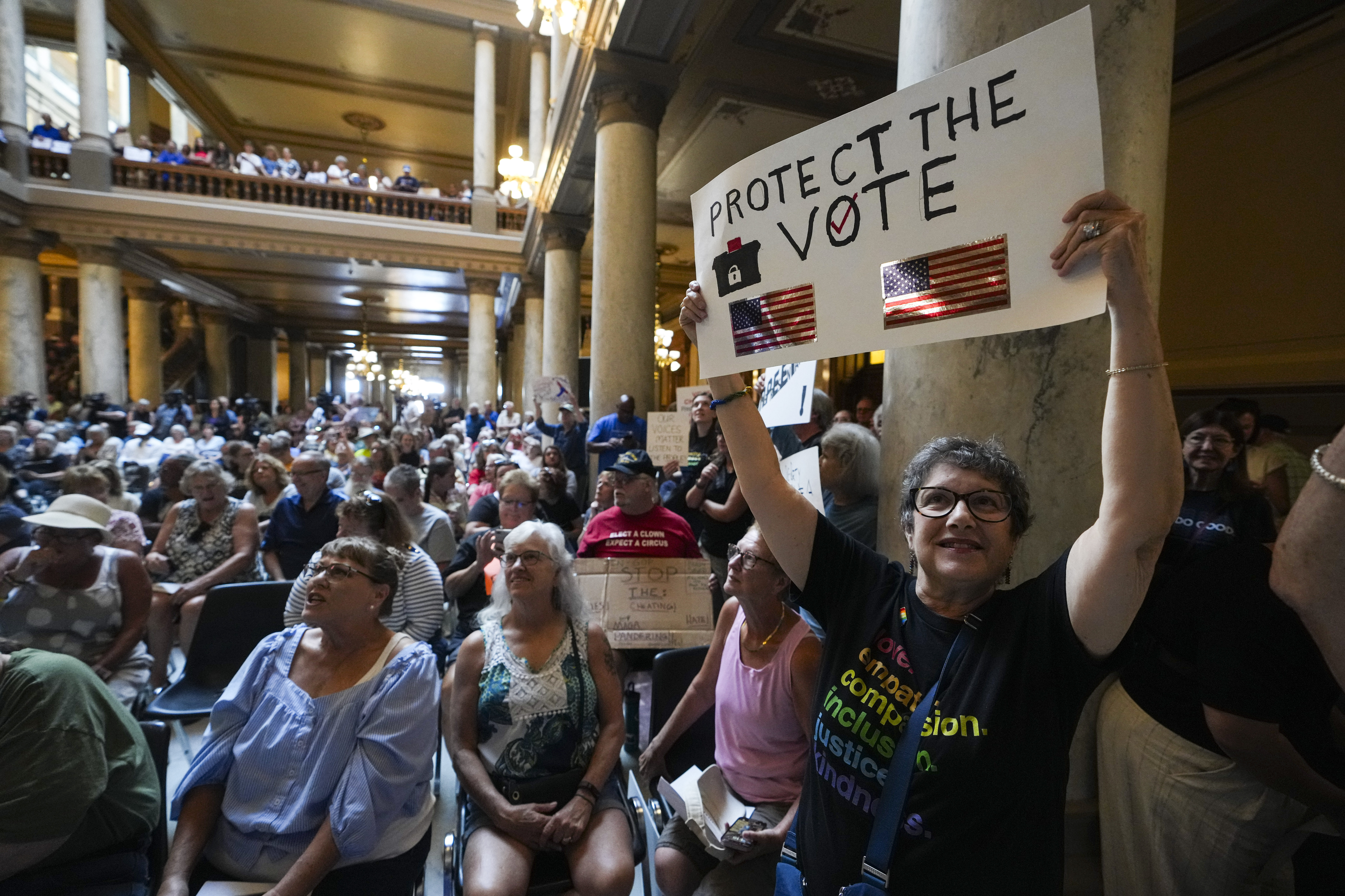 Annette Groos holds a sign before the start of a rally featuring former Transportation Secretary Pete Buttigieg at the Statehouse in Indianapolis, Thursday, Sept. 18, 2025 for Indiana Democrats amid pressure from President Donald Trump on Republicans who control the state's legislature to redistrict congressional seats. (Michael Conroy - AP)