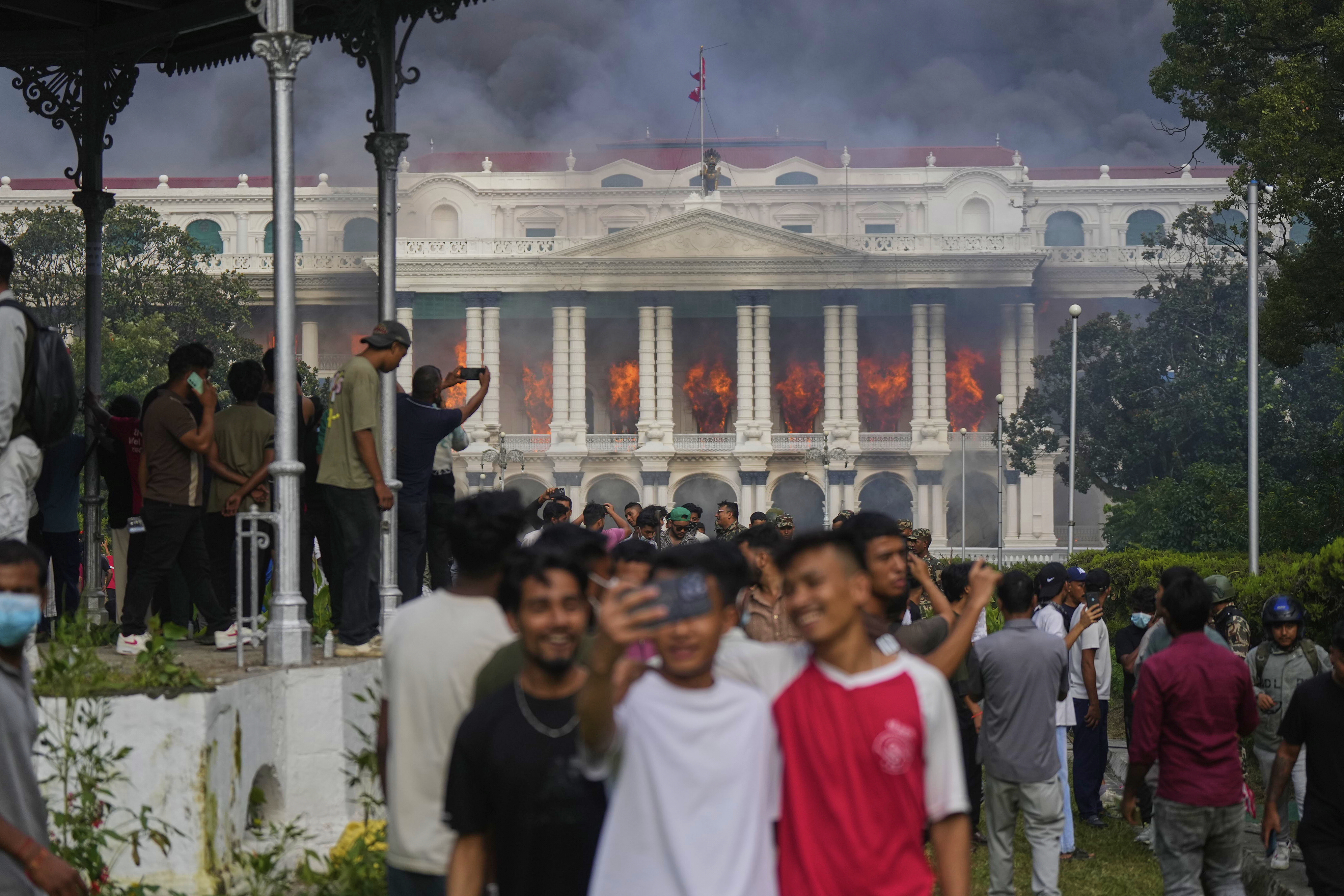 Protesters take selfies and celebrate at the Singha Durbar, the seat of Nepal's government's various ministries and offices, after it was set on fire during a protest against social media ban and corruption in Kathmandu, Nepal, Tuesday, Sept. 9, 2025. (Niranjan Shrestha - AP)