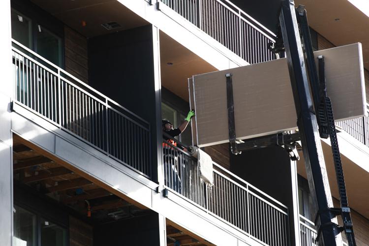 A construction worker grabs finishing components being craned in
