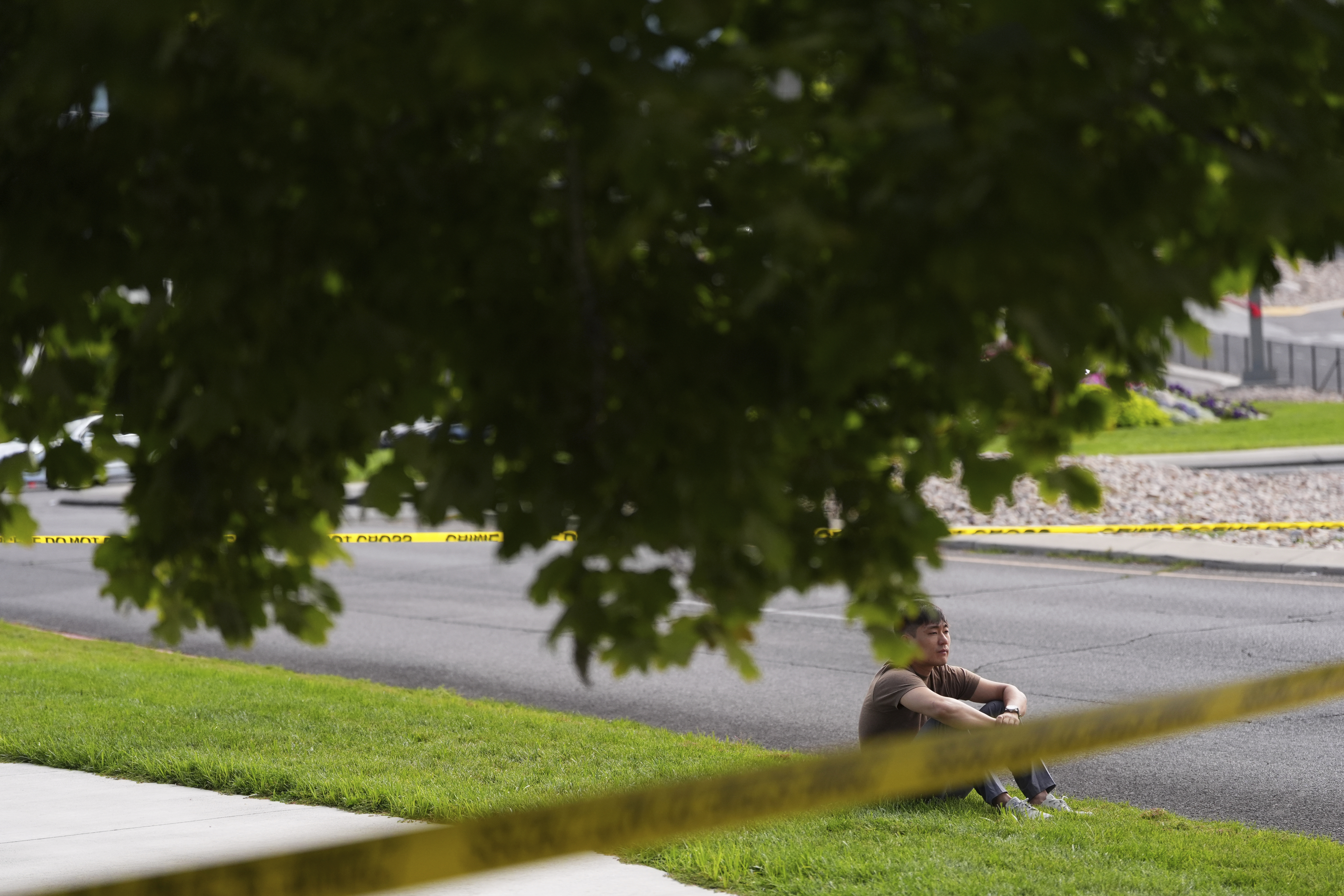 A person sits near crime scene tape near a memorial after Turning Point USA CEO and co-founder Charlie Kirk was shot and killed at Utah Valley University, Saturday, Sept. 13, 2025, in Orem, Utah. (Lindsey Wasson - AP)