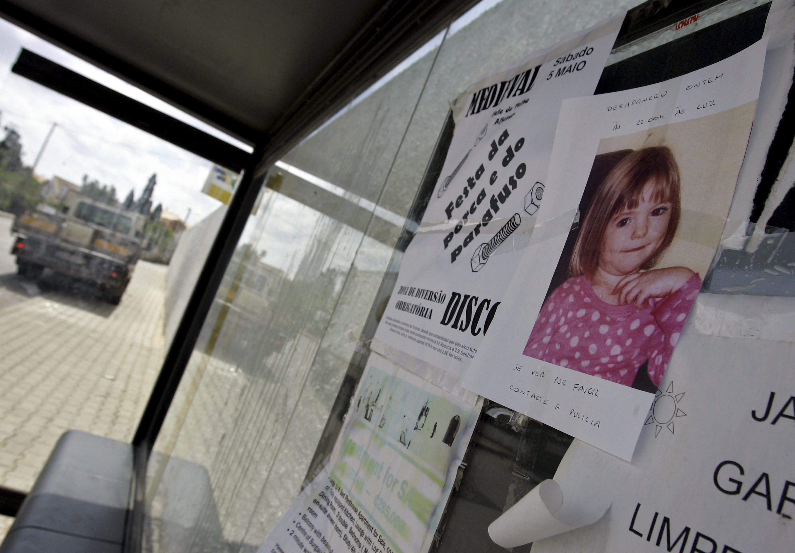 FILE -A photo of 3-year-old British girl Madeleine McCann is pasted on a board at a bus stop near the resort from where she went missing, May 4, 2007, in Praia da Luz, southern Portugal, where she was on vacation with her family. (ARMANDO FRANCA - AP)