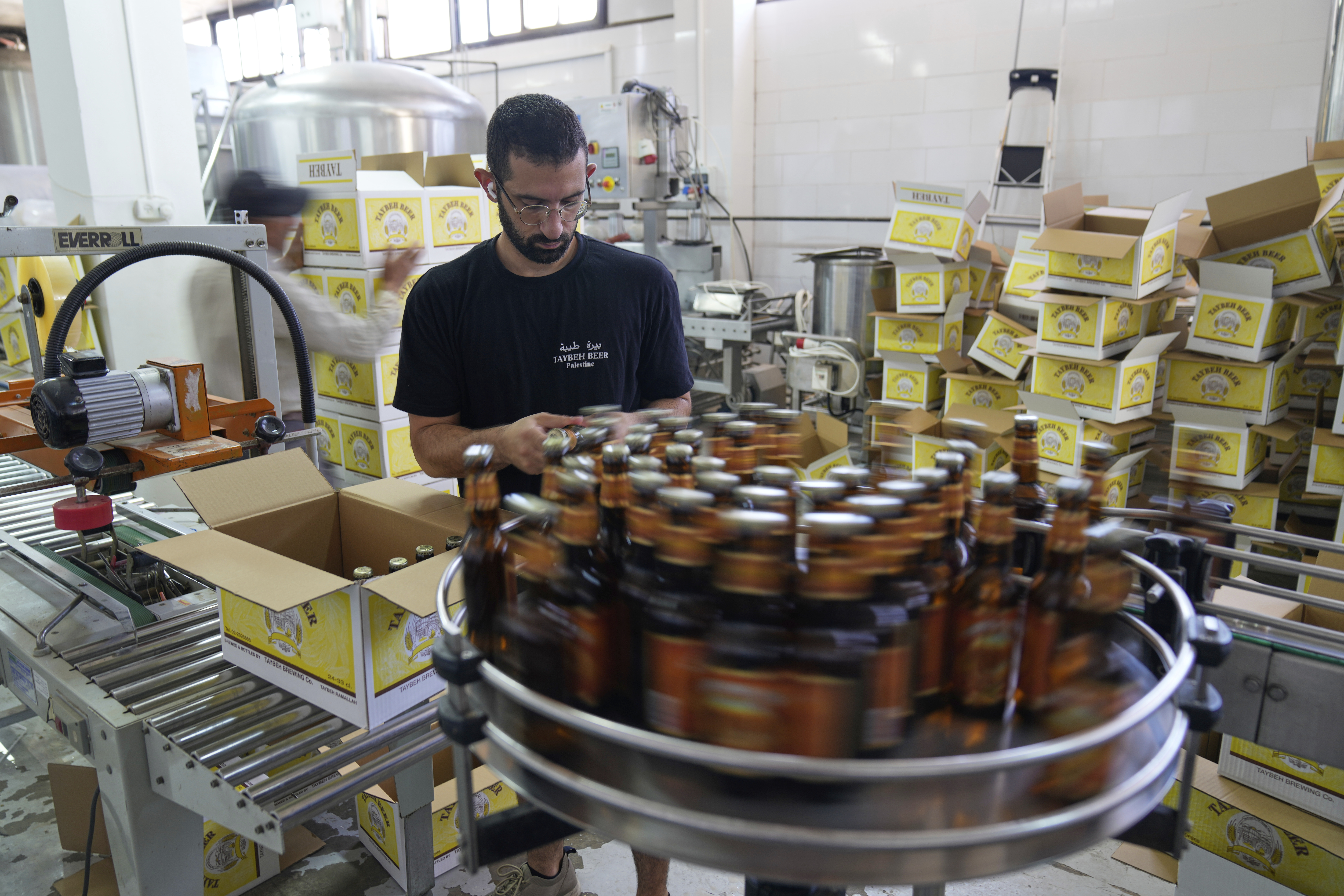 Canaan Khoury packs Taybeh beer bottles into boxes on a production line of the family's Palestinian Taybeh Brewery Co. in the West Bank town of Taybeh, Saturday, Sept. 6, 2025. (Nasser Nasser - AP)