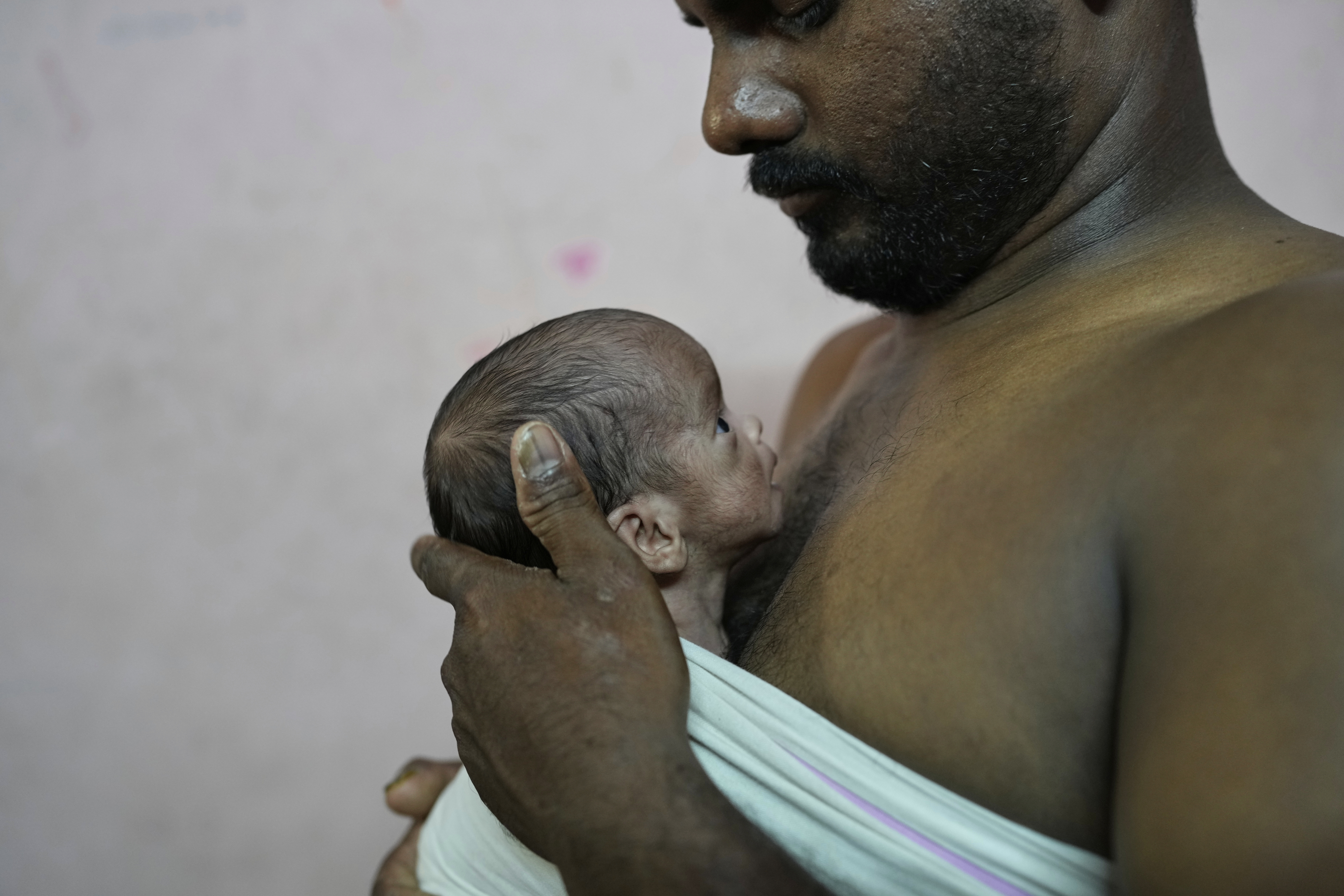 Sikander Chaudhary gives the Kangaroo Mother Care (KMC), a method of holding a baby skin-to-skin on the caregiver's chest, to promote bonding and well-being, to his newborn son in his house in Gurugram, a satellite city of New Delhi, India, Friday, Aug. 8, 2025. (Manish Swarup - AP)
