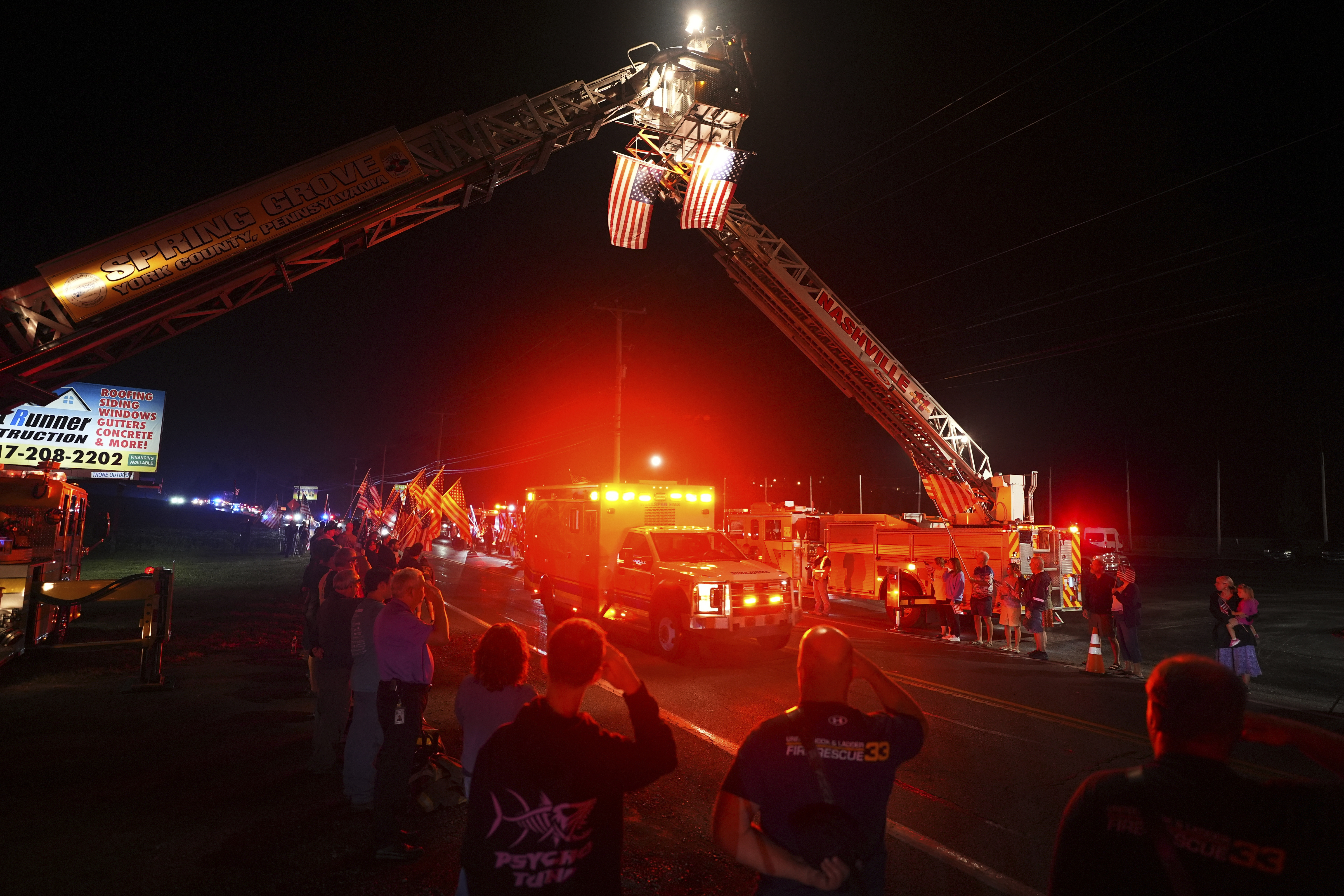 People salute as an ambulance drives past during a procession Wednesday, Sept. 17, 2025, in Spring Grove, Pa., after multiple police officers were shot and killed. (Matt Slocum - AP)