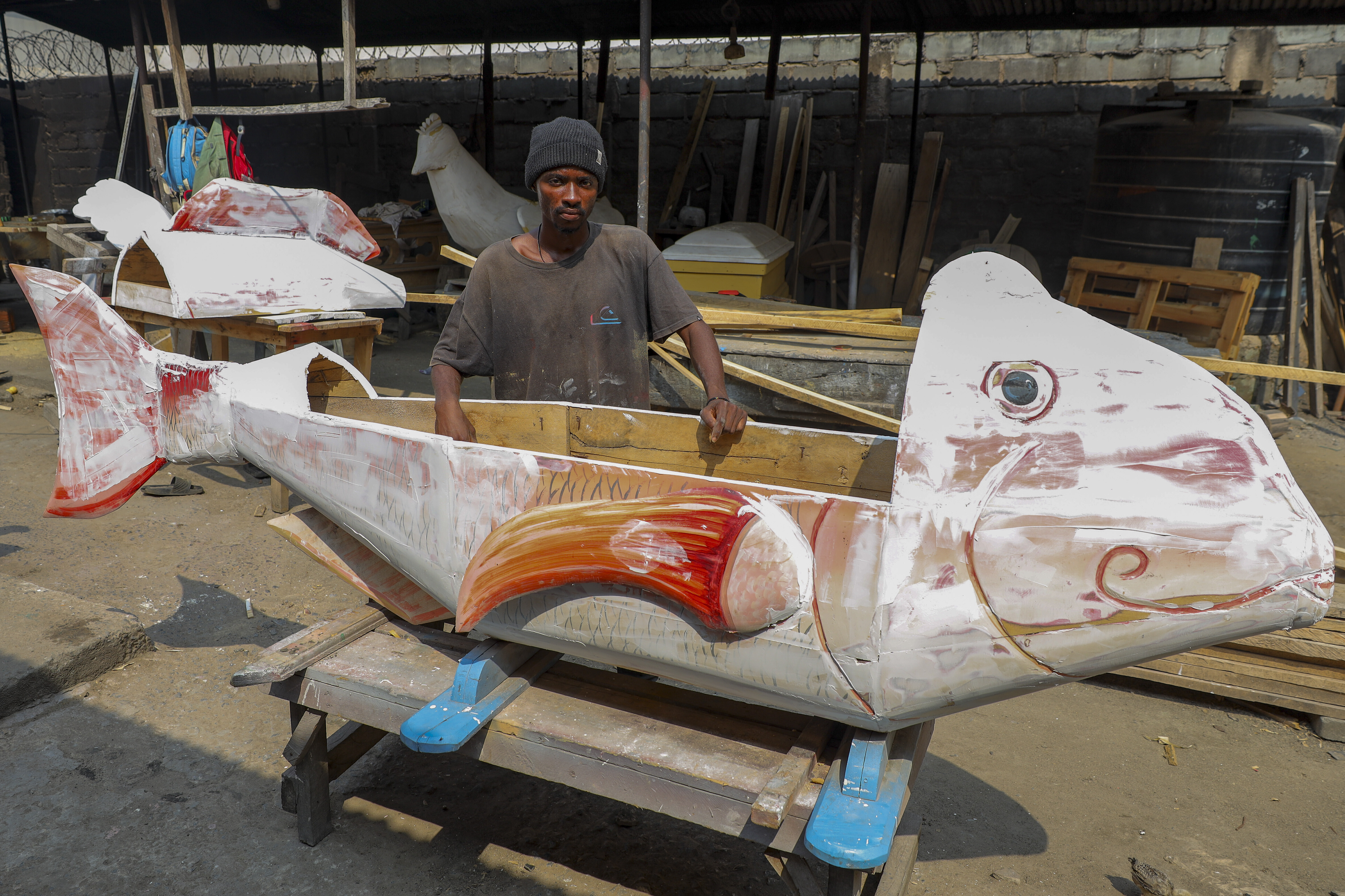 Nicholas Ablorh Annan, poses by a fish-shaped fantasy coffin in production, at his father's workshop in Teshie, Accra, Ghana, Tuesday, July 29, 2025. (Misper Apawu - AP)