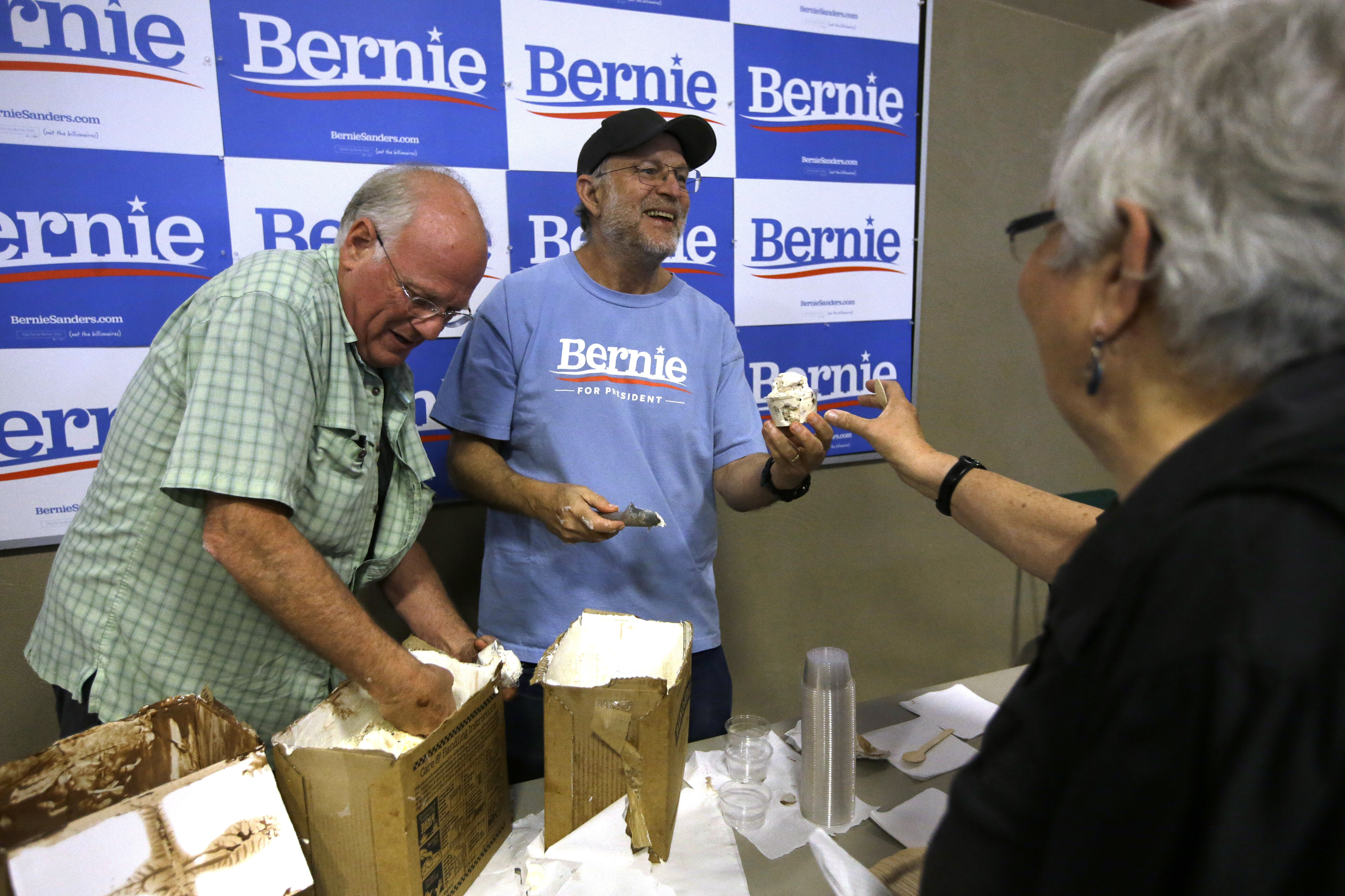 FILE - Ben & Jerry's co-founder Ben Cohen, left, and fellow co-founder Jerry Greenfield, center, scoop ice cream before a campaign event for Sen. Bernie Sanders, I-Vt., not shown, Sept. 1, 2019, in Raymond, N.H. (Steven Senne - AP)