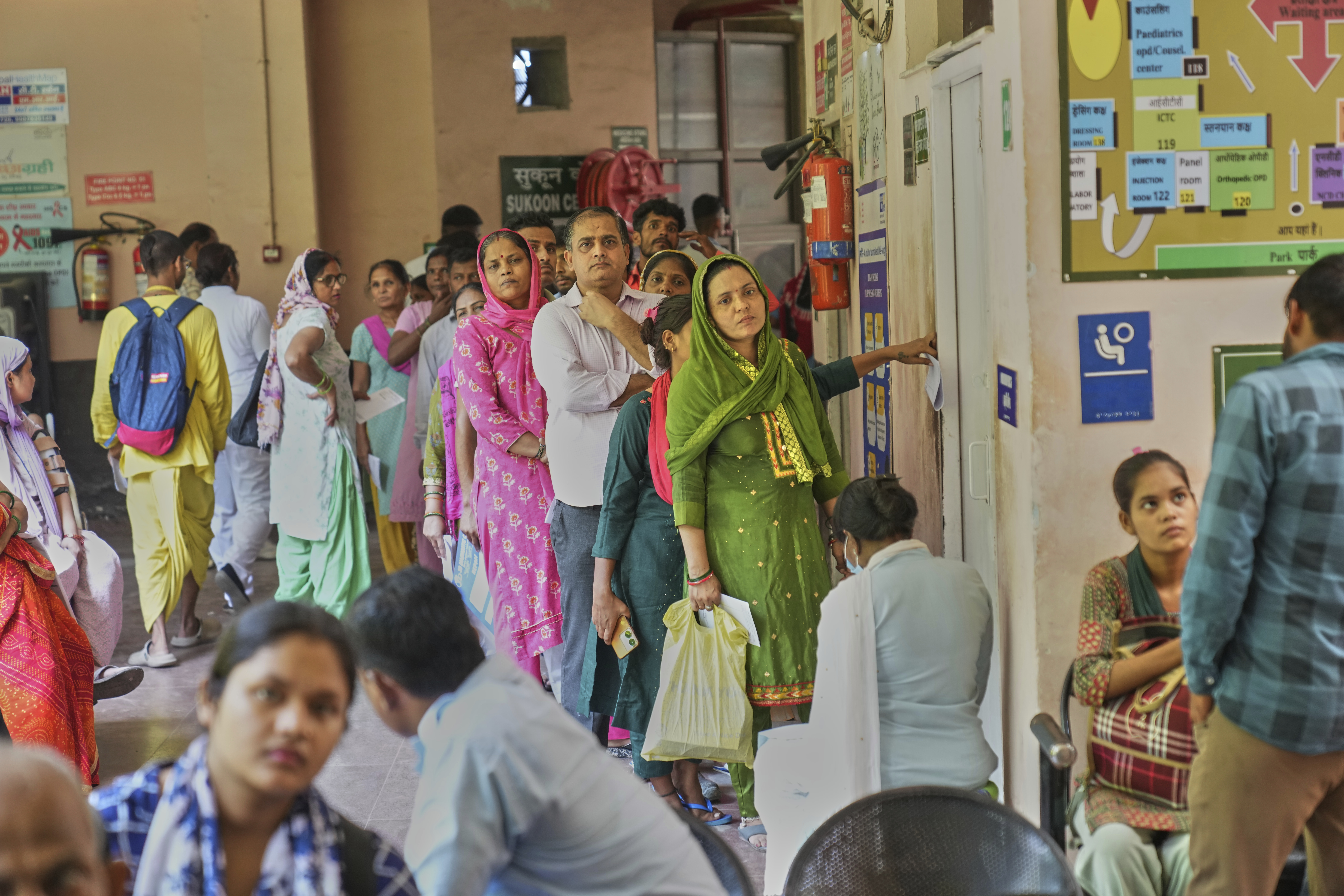 Patients stand in a queue outside a doctor's room while they watch a Care Companion Program (CCP) session at a government hospital in Gurugram, a satellite city of New Delhi, India, on Aug. 7, 2025. (Manish Swarup - AP)