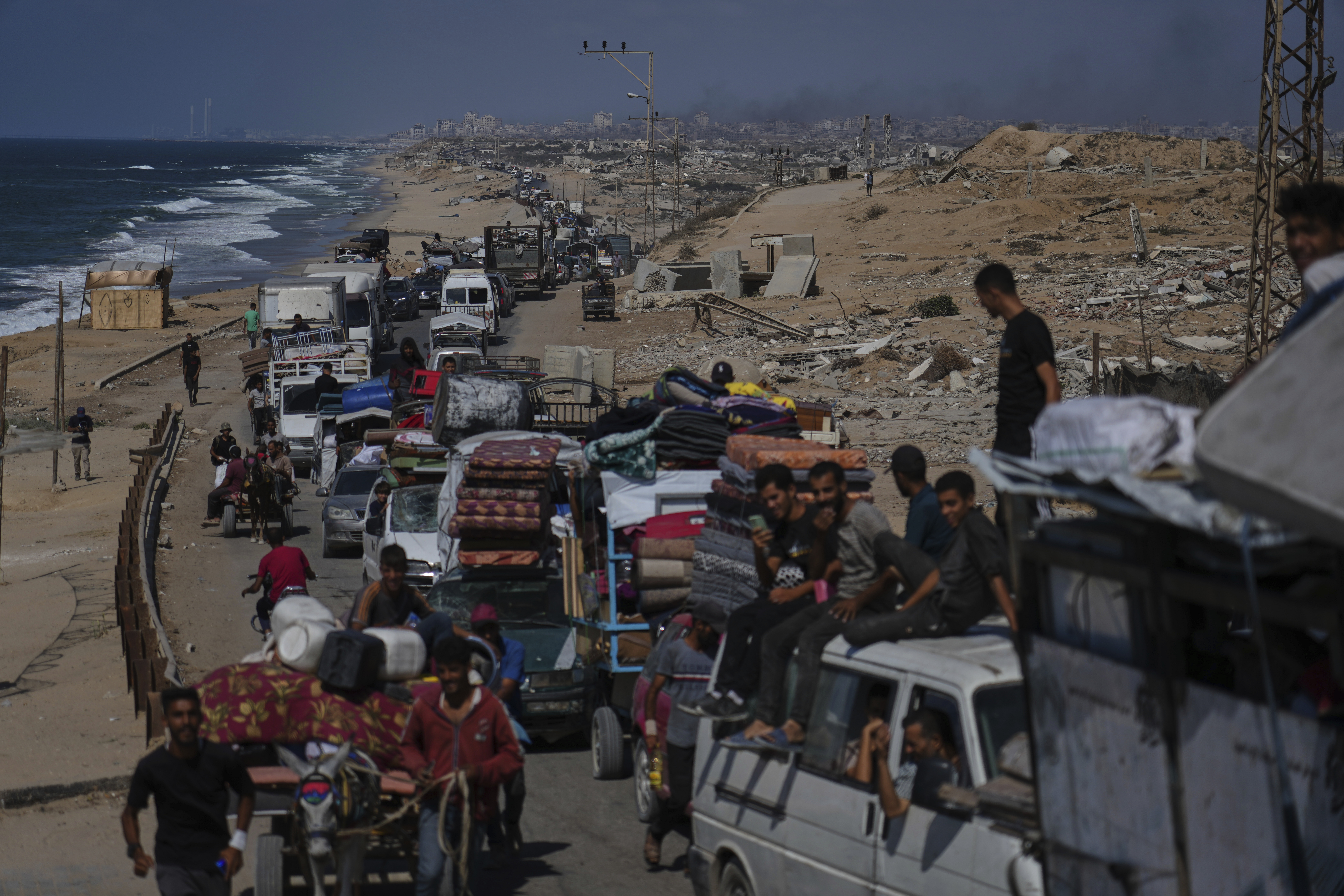 Displaced Palestinians fleeing northern Gaza carry their belongings along the coastal road toward southern Gaza, Tuesday, Sept. 9, 2025, after the Israeli army issued evacuation orders from Gaza City. (Jehad Alshrafi - AP)