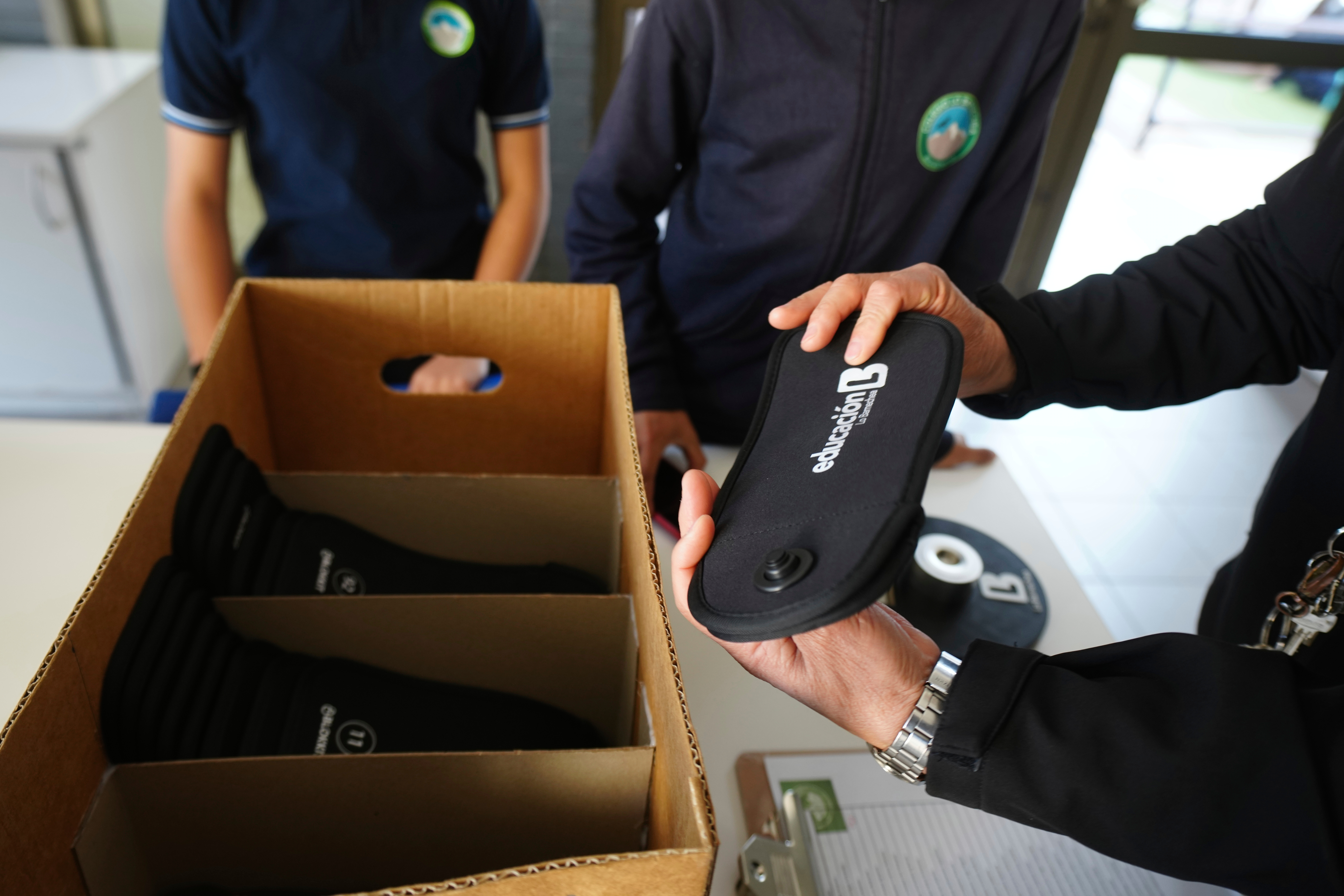 A professor passes out cell phone signal jammers to students to place their cell phones into, as part of a pilot program to reduce mobile use during school hours, at Bicentenario School in Santiago, Chile, Monday, Sept. 8, 2025. (Esteban Felix - AP)