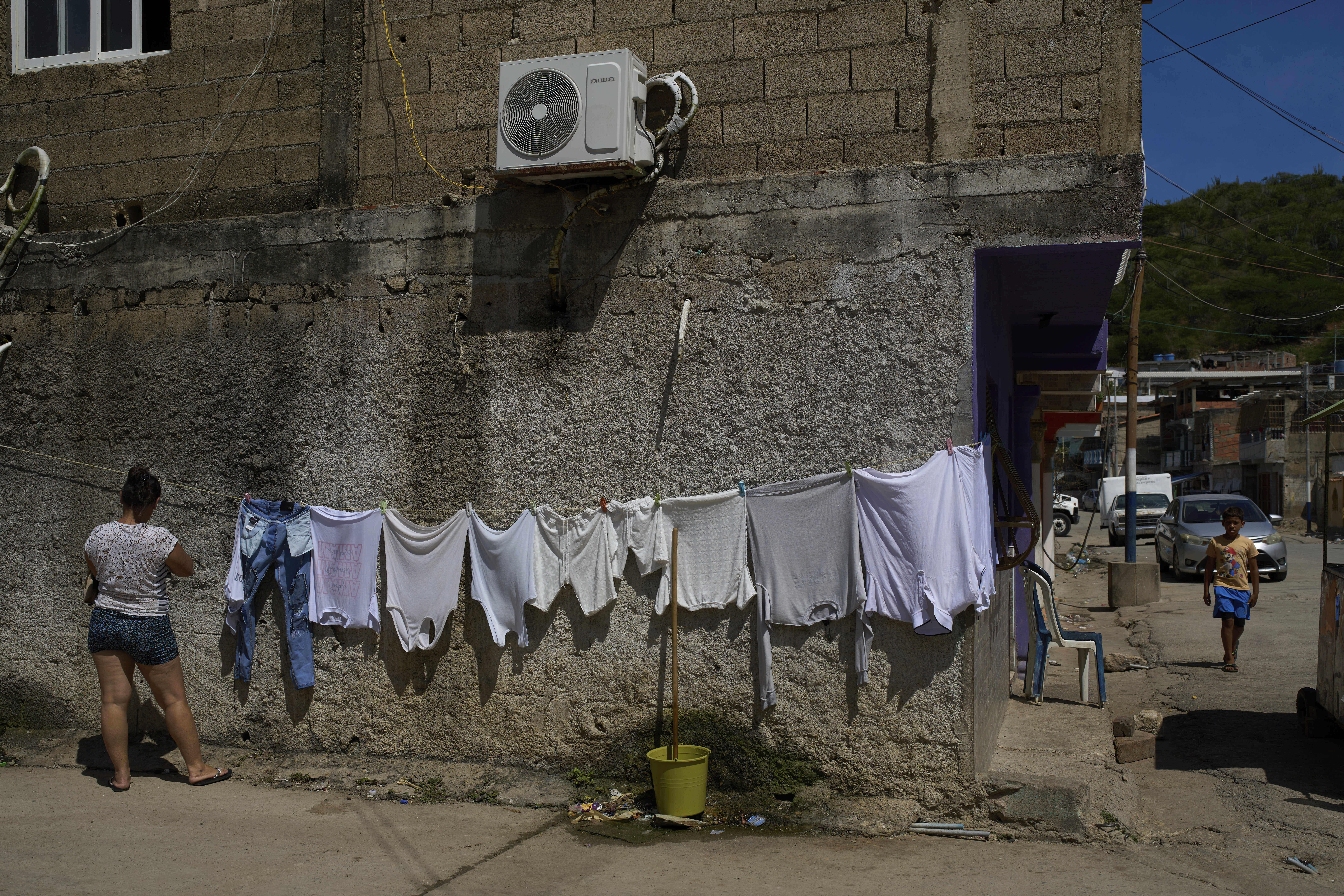 A woman hangs clothes to dry in the fishing community of El Morro de Puerto Santo, on Venezuela's Paria Peninsula, Sunday, Sept. 14, 2025. (Ariana Cubillos - AP)
