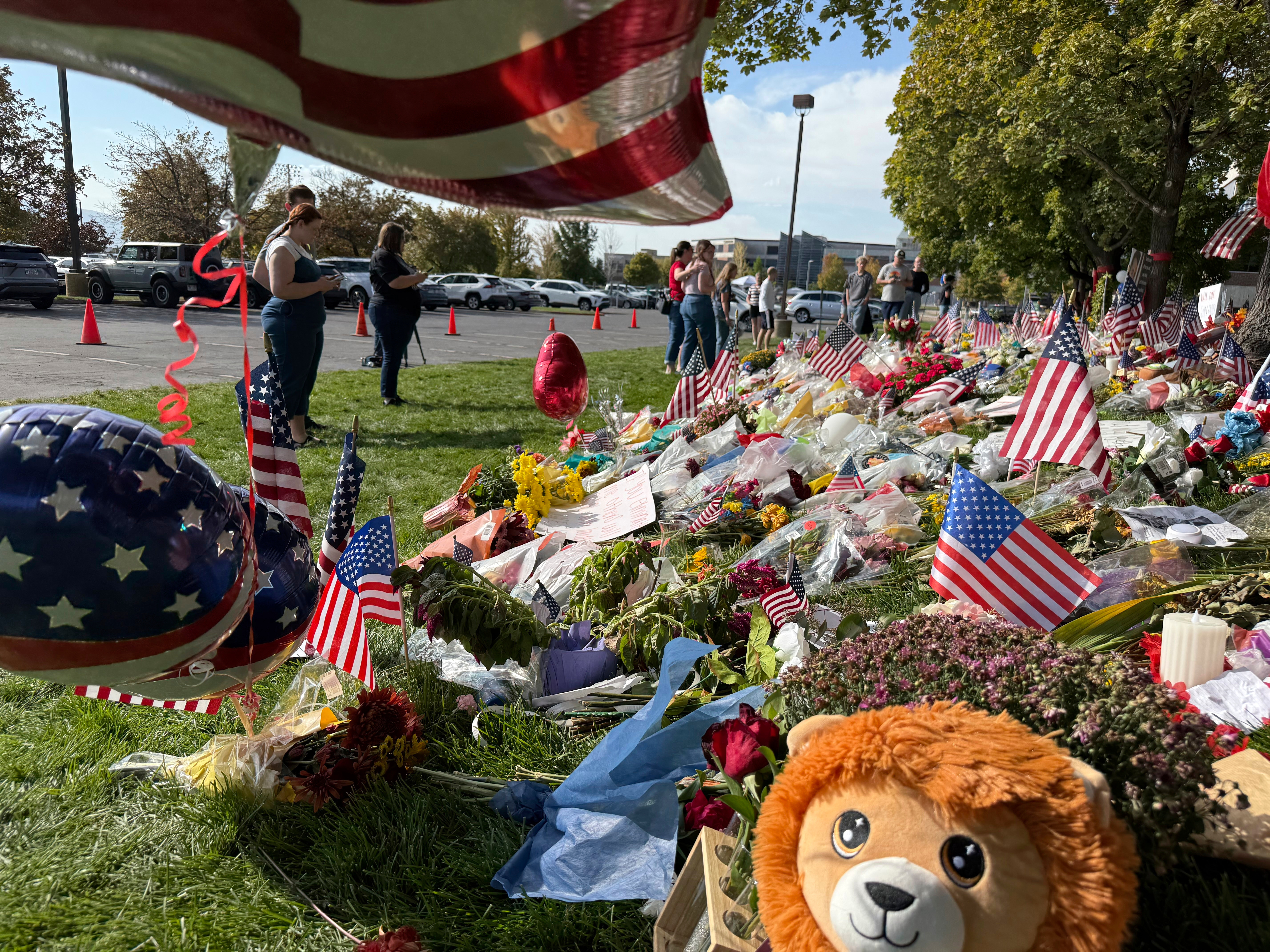 People bring flowers and write messages in chalk at a memorial for Charlie Kirk at Utah Valley University, on Monday, Sept. 15, 2025, in Orem, Utah. (Jesse Bedayn - AP)