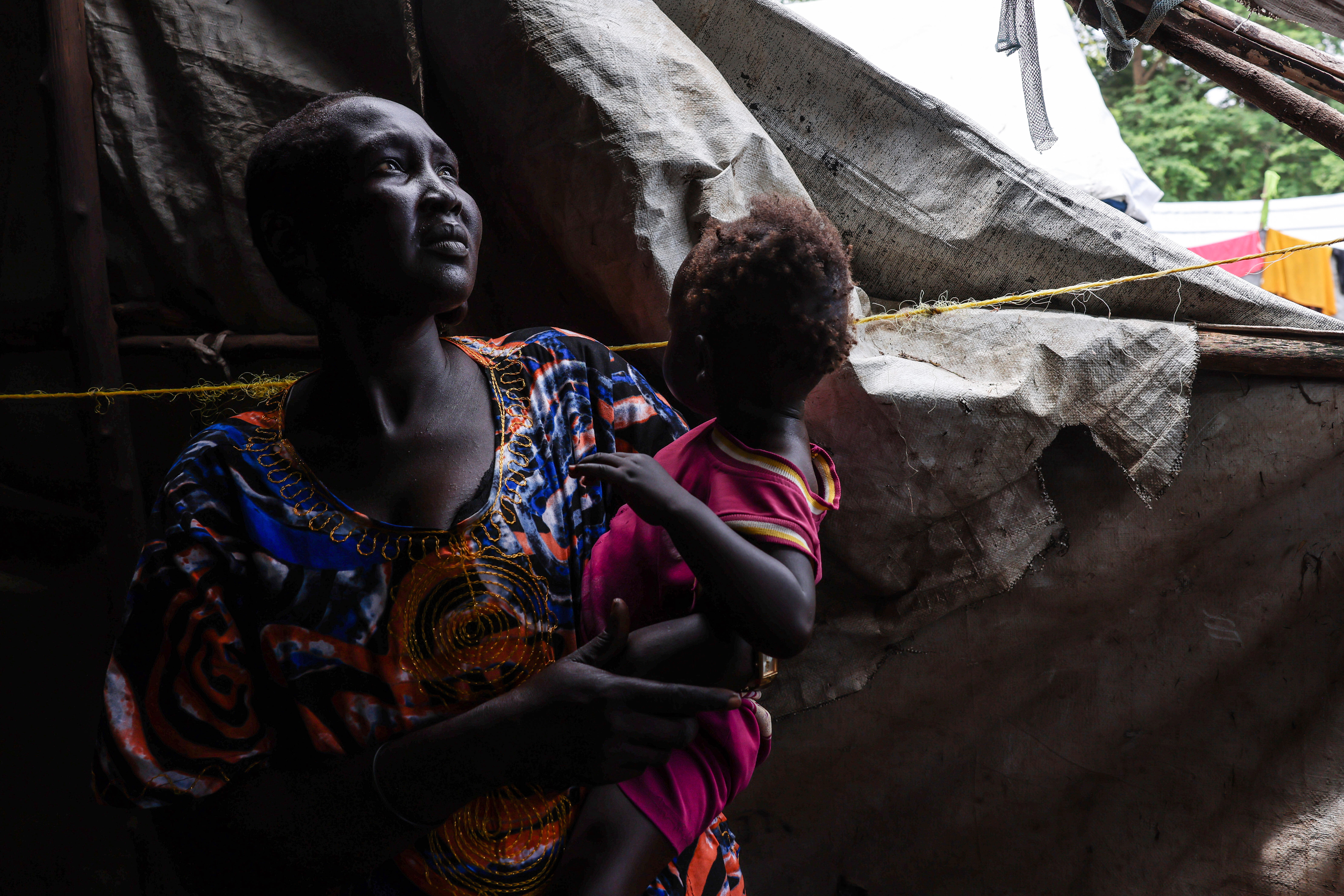 Rebekah Nyekhor, 31 years old, a mother of five, stands inside her makeshift home, carrying her child, in an IDP camp on the outskirts of Bor, South Sudan, Monday, Aug. 18, 2025. (Caitlin Kelly - AP)