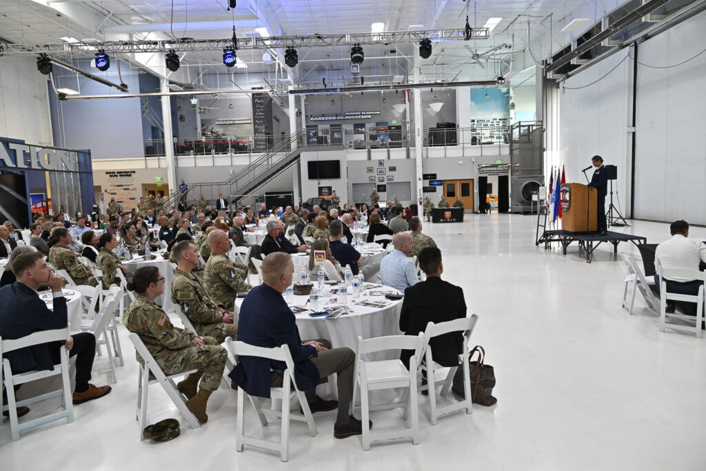 people seated at tables in an aircraft hangar