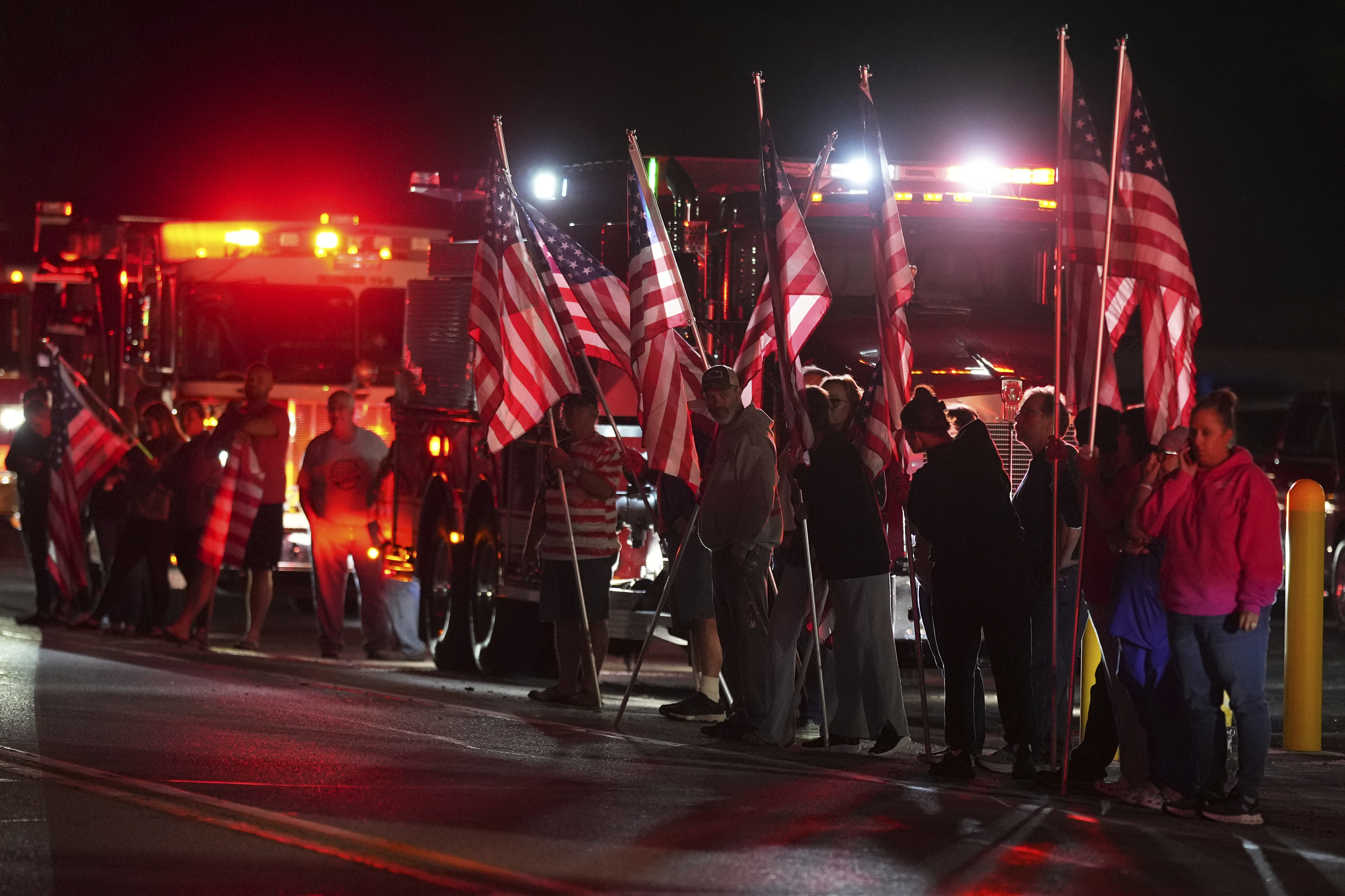 People hold American flags before a procession Wednesday, Sept. 17, 2025, in Spring Grove, Pa., after multiple police officers were shot and killed. (Matt Slocum - AP)