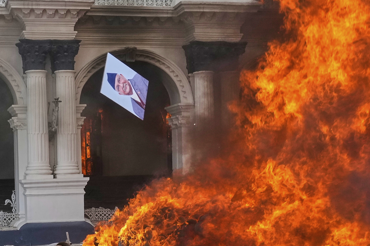 A protester throws a photograph of Nepal Prime Minister Khadga Prasad Oli in the fire at the Singha Durbar, the seat of Nepal's government's various ministries and offices during a protest against social media ban and corruption in Kathmandu, Nepal, Tuesday, Sept. 9, 2025. (Niranjan Shrestha - AP)