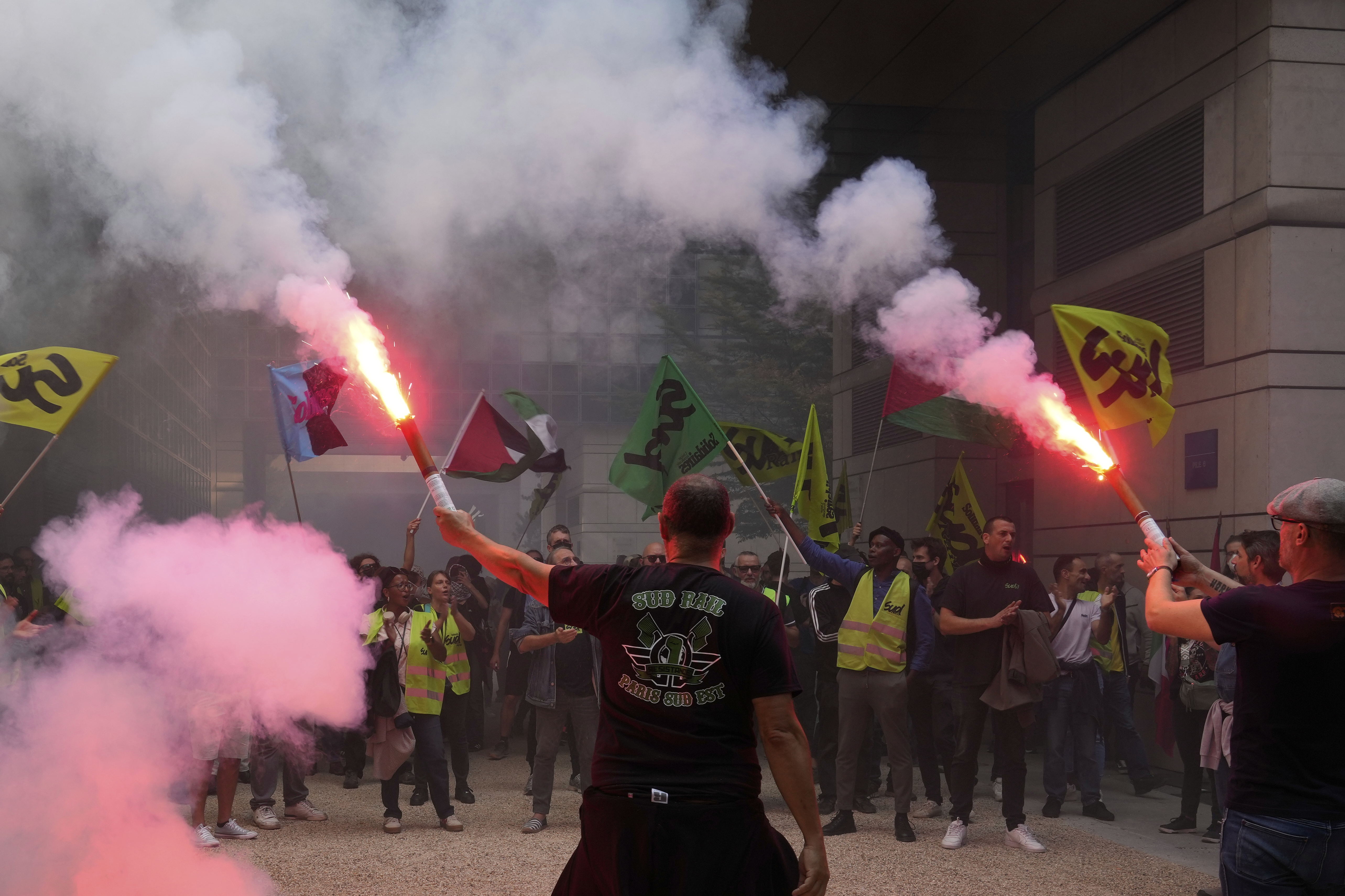 Striking rail workers wave flares into the Paris headquarters of the Economics Ministry during a protest called by major trade unions to oppose budget cuts, in Paris, France, Thursday, Sept. 18, 2025. (Michel Euler - AP)