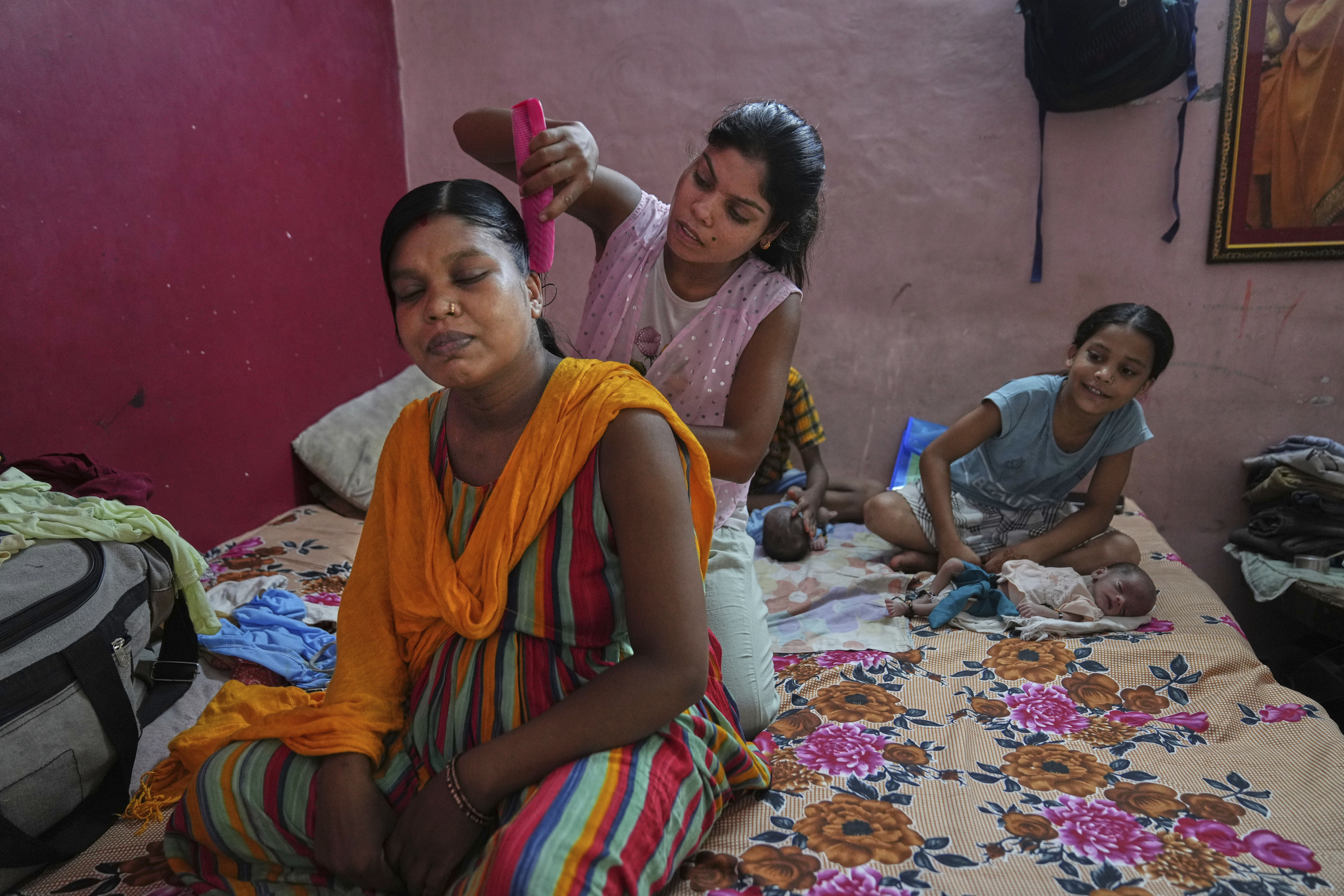 Antima Kumari, center, trained in Care Companion Program (CCP), combs the hair of her sister Lilawati, who delivered twins, at their house in Gurugram, a satellite city of New Delhi, India, on Aug. 8, 2025. (Manish Swarup - AP)