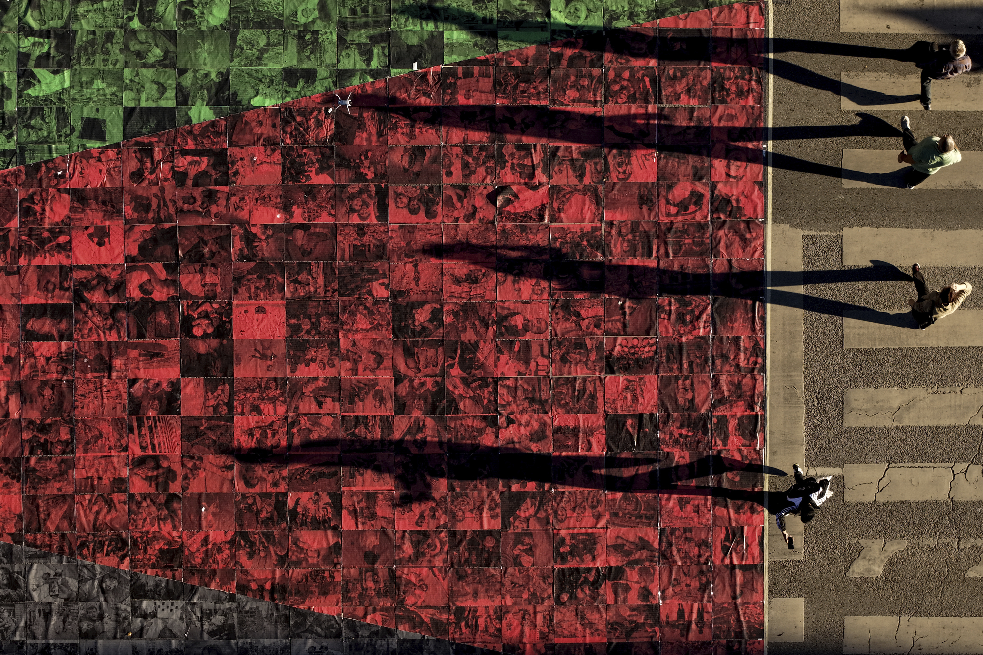 An aerial view shows people marching next to the Palestinian flag made of photographs of people killed, displayed on a street during a protest in support of Palestinians in Hadzici, suburb of Sarajevo, Bosnia, Saturday, Sept. 20, 2025. (Armin Durgut - AP)