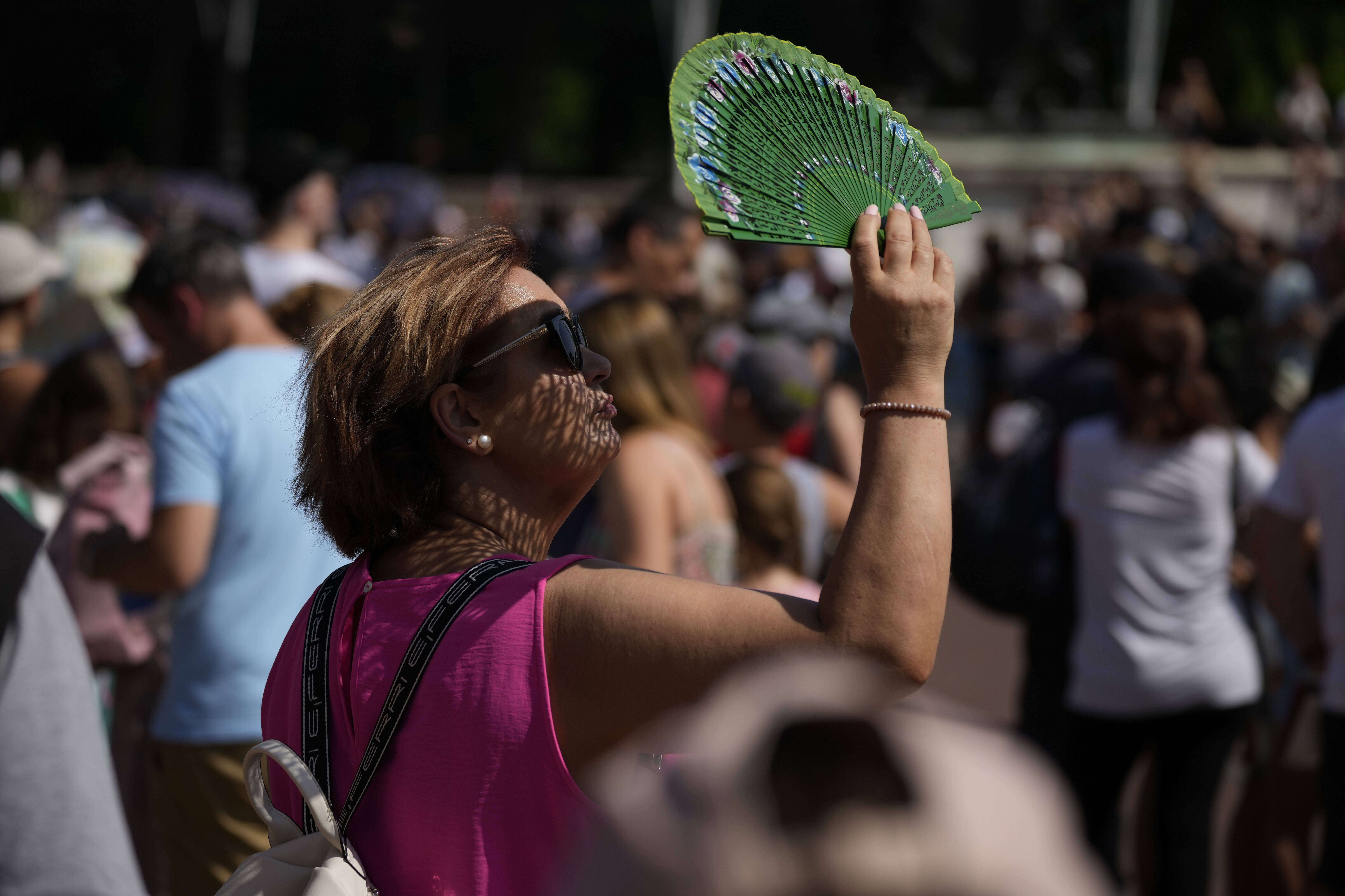 FILE - A tourist uses a fan to shade her face from the sun while waiting to watch the Changing of the Guard ceremony outside Buckingham Palace, during hot weather in London, July 18, 2022. (Matt Dunham - AP)